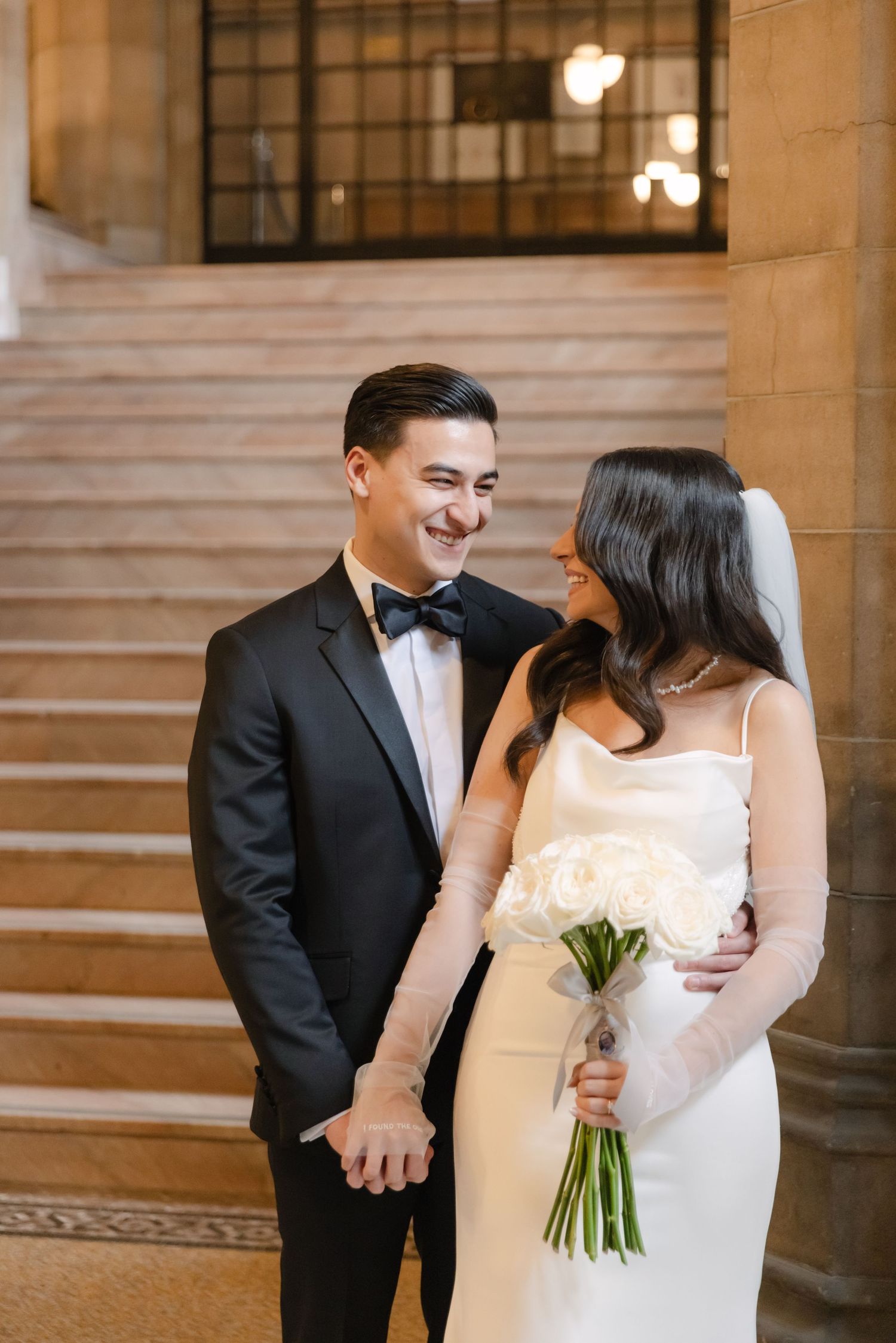 Intimate moment between newlyweds with bride holding white bouquet in classic venue setting.