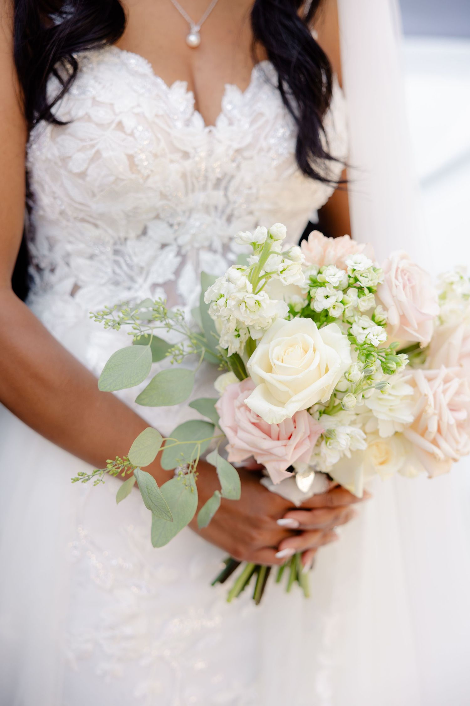Detailed shot of bridal bouquet featuring cream roses, eucalyptus and delicate white flowers.
