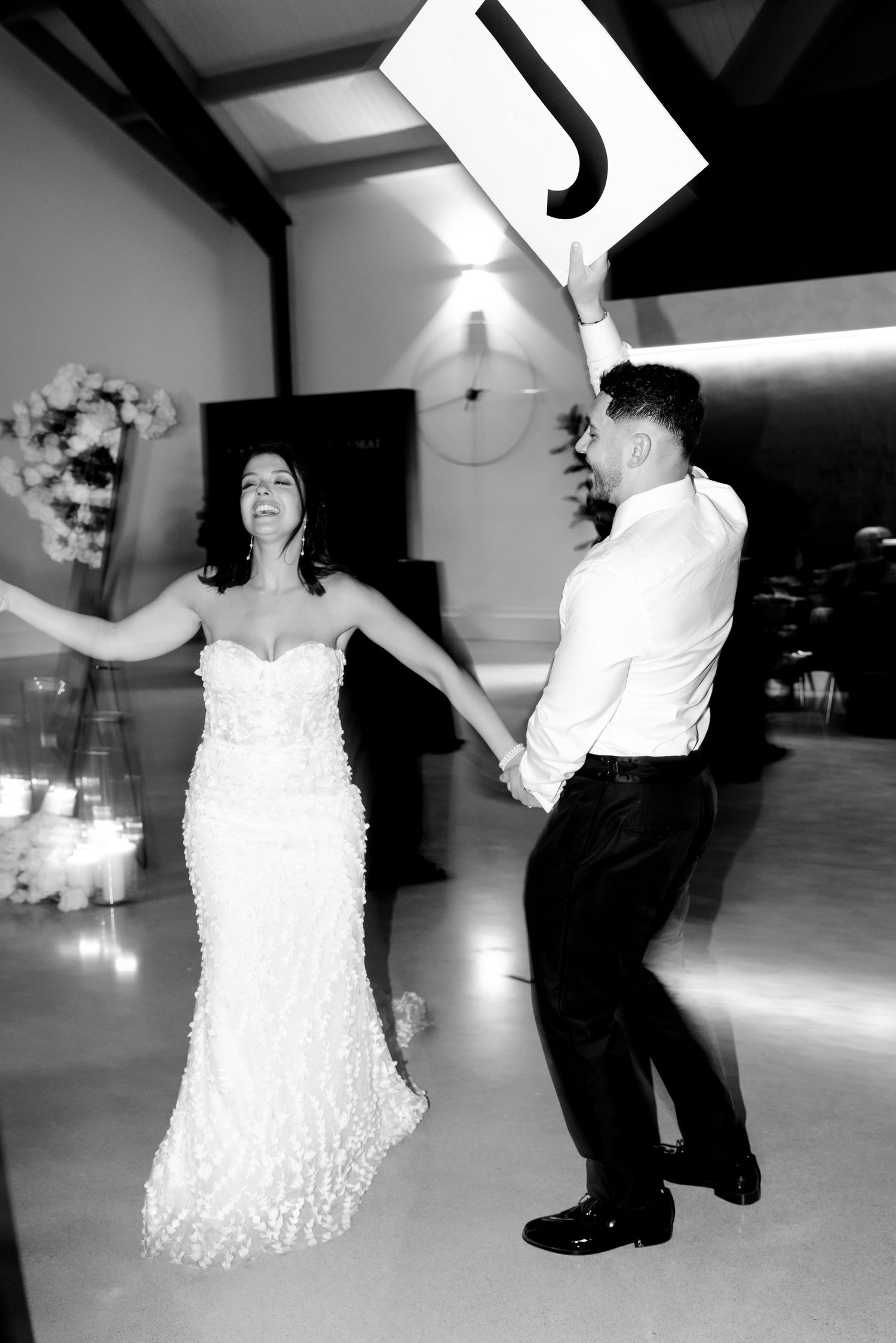 Black and white photo of a couple dancing energetically at their wedding reception.