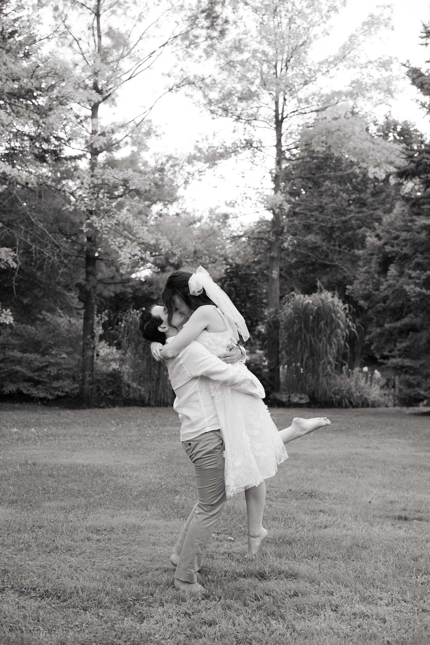 Black and white photo of a joyful lift pose during an outdoor wedding session.