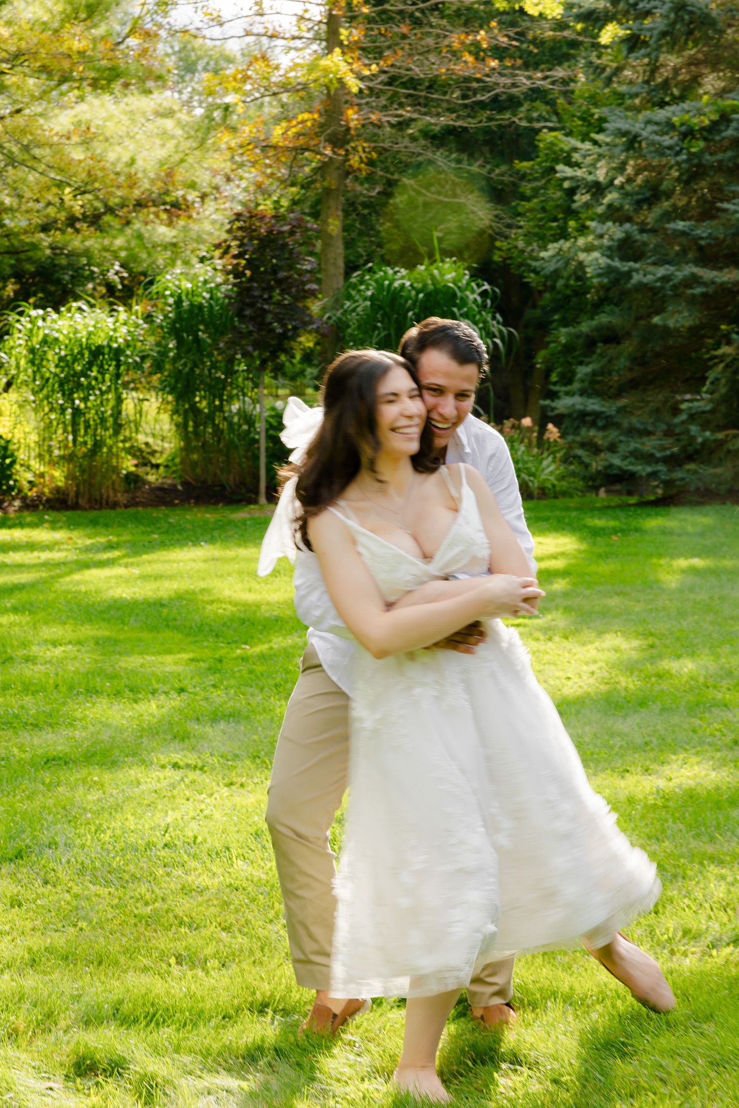 A tender embrace captured in warm sunlight against green garden scenery.