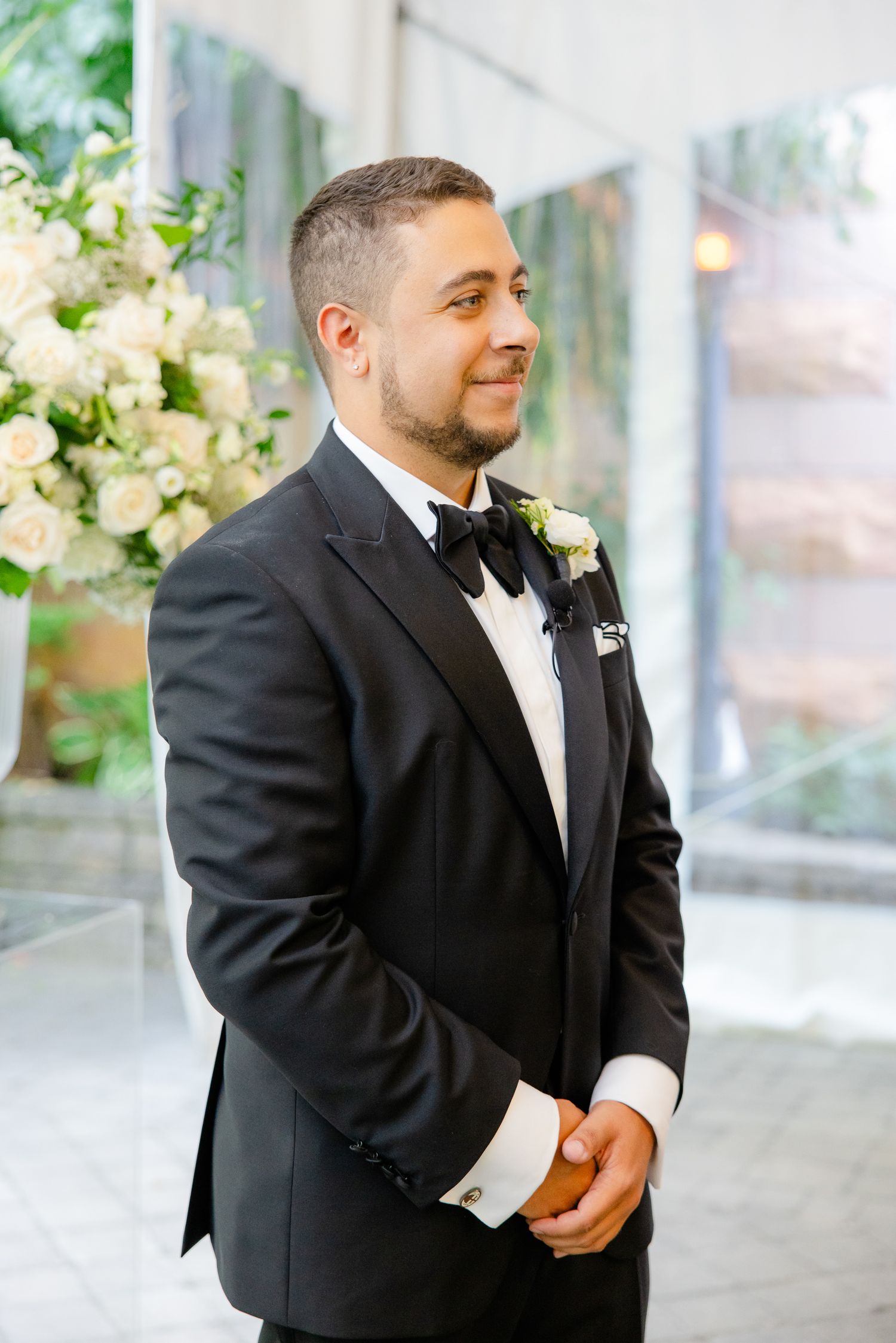 Groom in classic black tuxedo and bowtie poses during wedding ceremony.