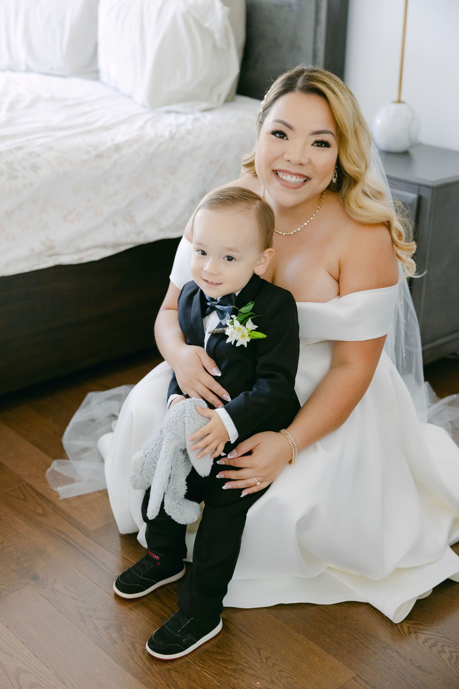 A heartwarming moment between a bride in white and a small child in formal attire sitting together.