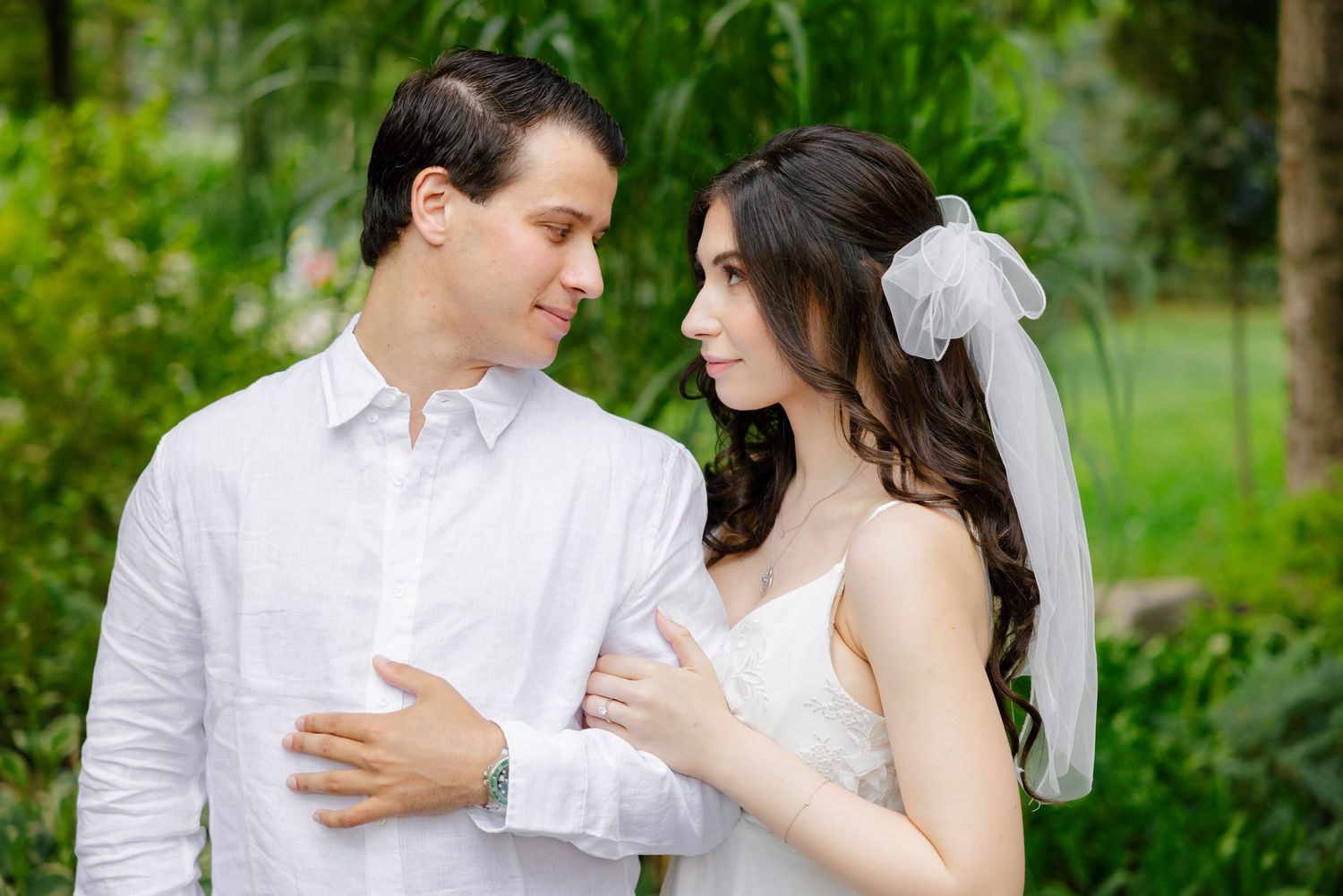An intimate wedding portrait of a couple gazing at each other in a garden.