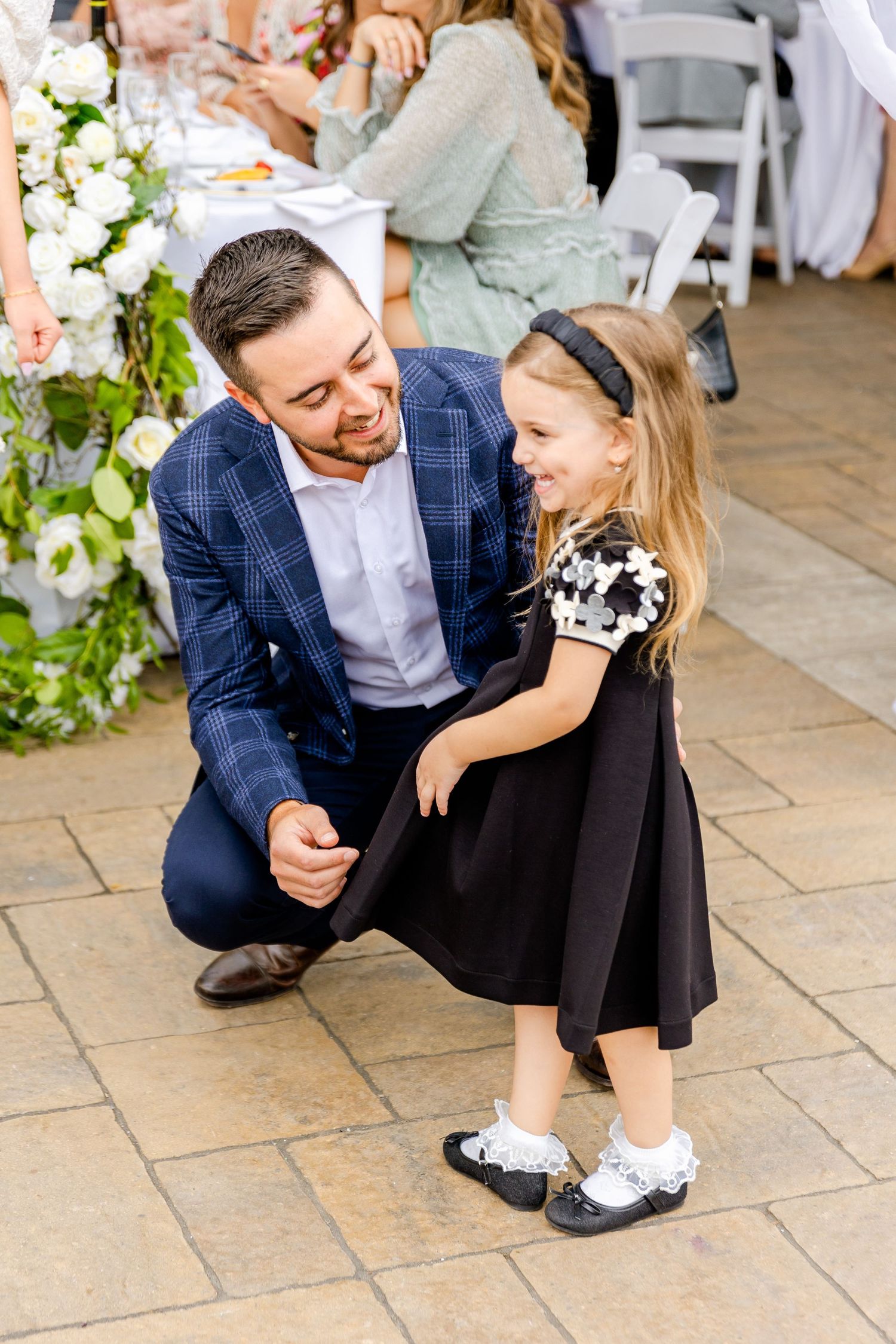 Sweet interaction between guests at a formal outdoor celebration with floral decorations.