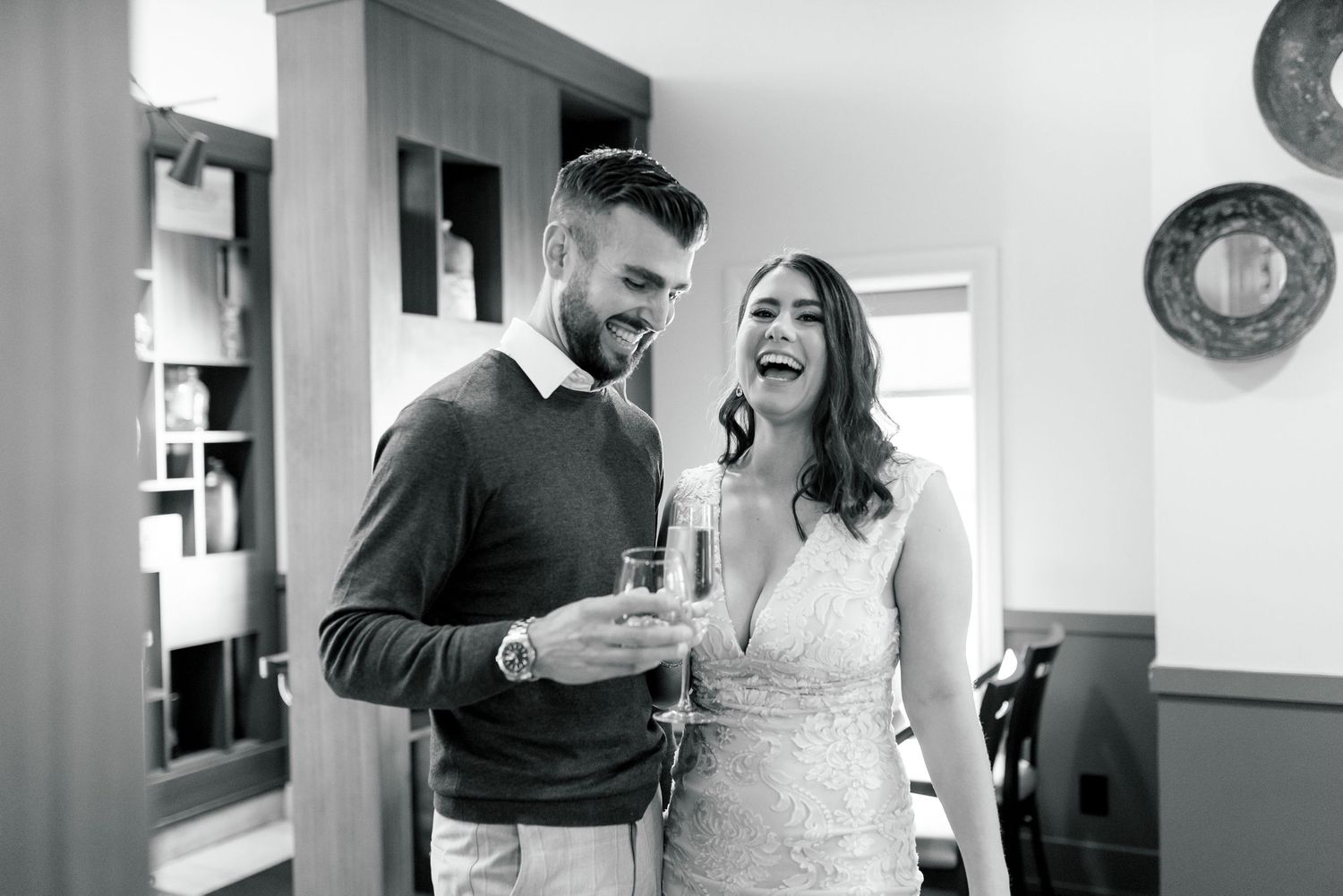 A couple sharing laughter while looking at something together in a bright interior space.