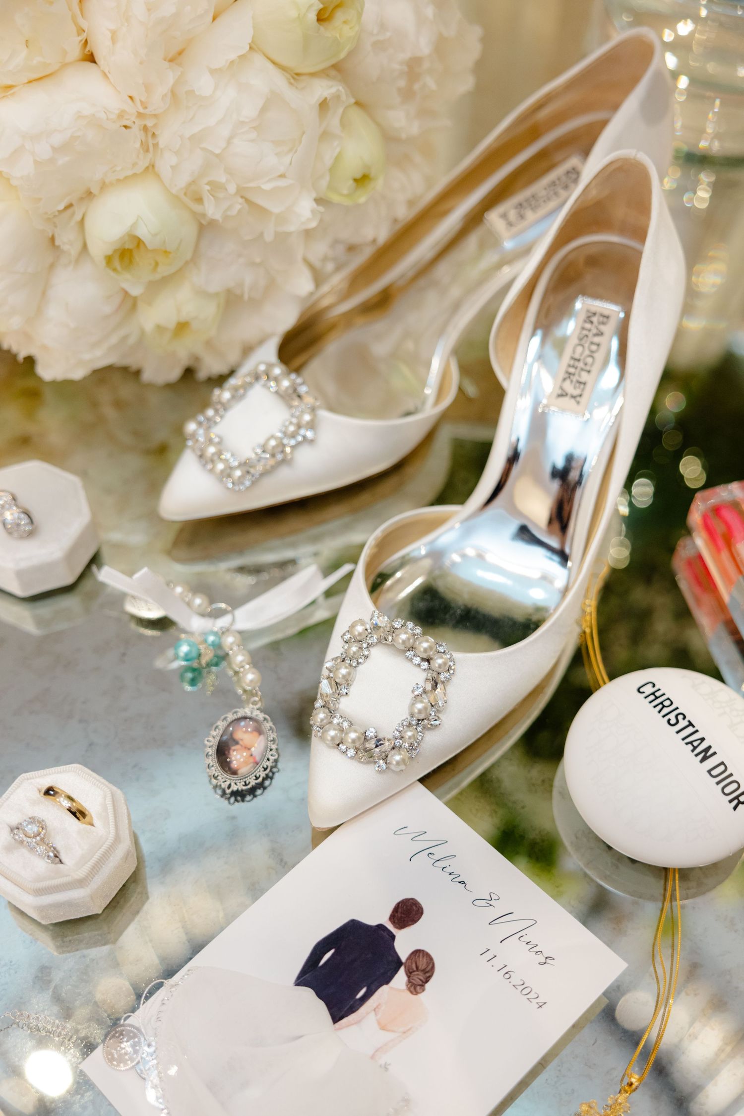Elegant white bridal shoes with crystal embellishments next to floral bouquet and wedding details.