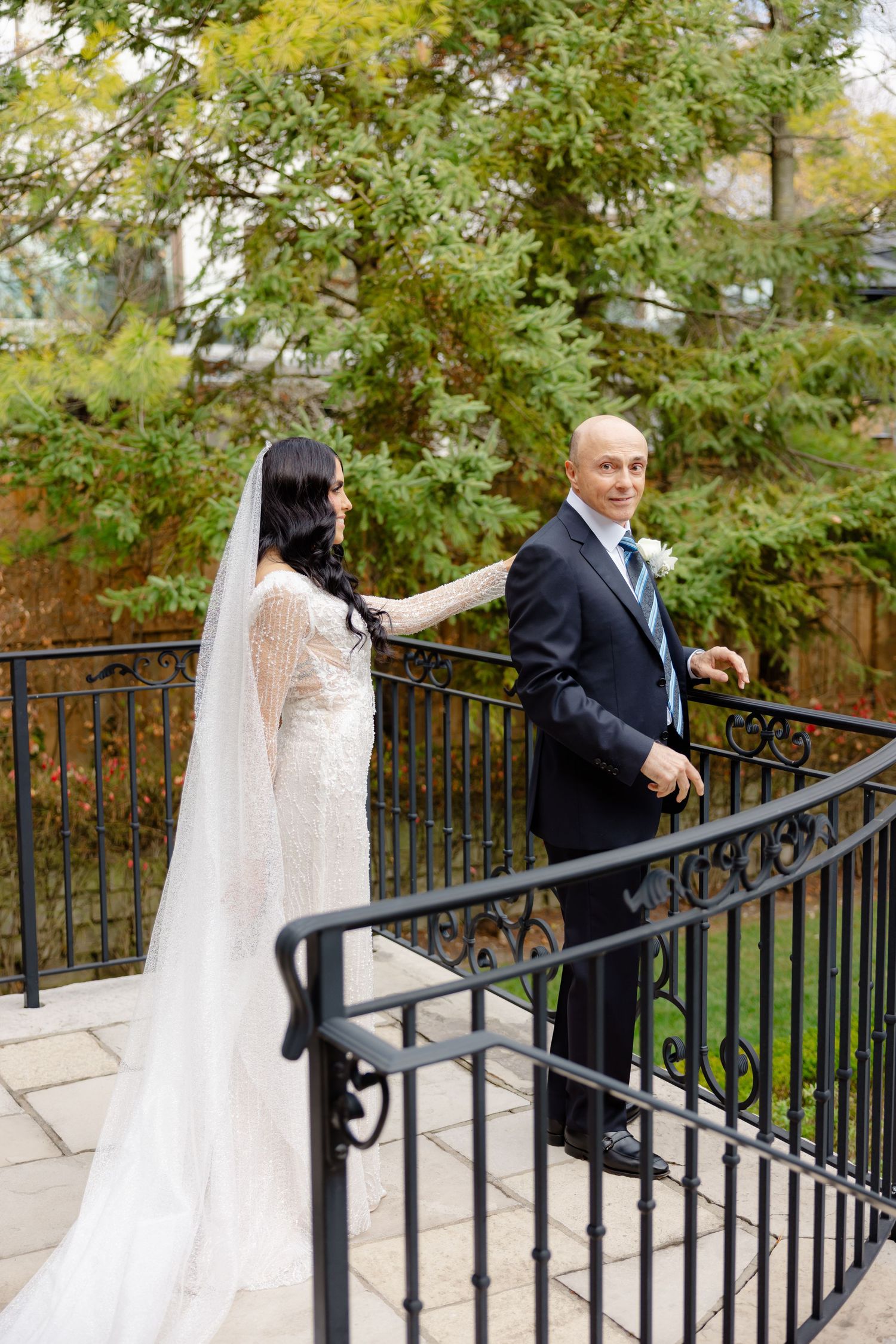 Wedding couple share first look moment on outdoor stone staircase with iron railings.