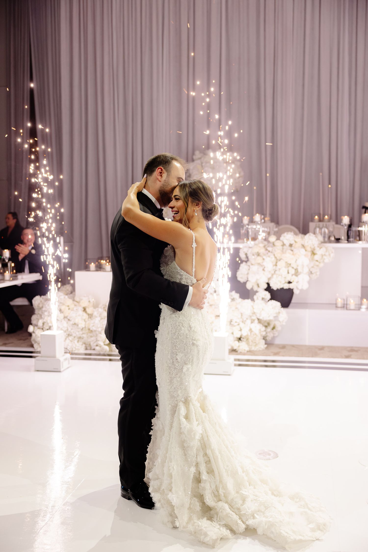 A couple shares their first dance at a wedding reception with sparkling cold sparklers creating a magical atmosphere.