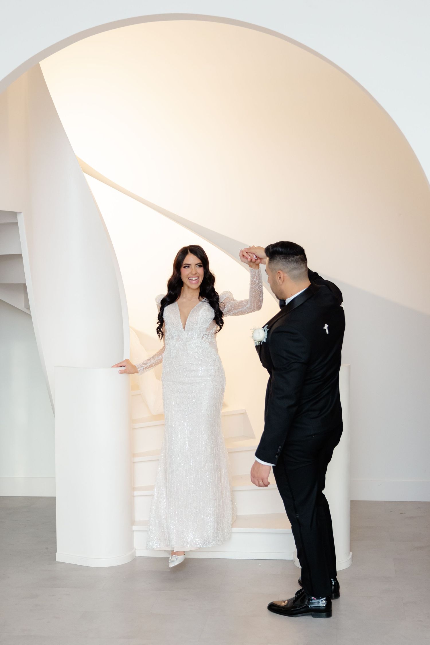 Couple shares a romantic moment on minimalist white stairs during their wedding photoshoot.