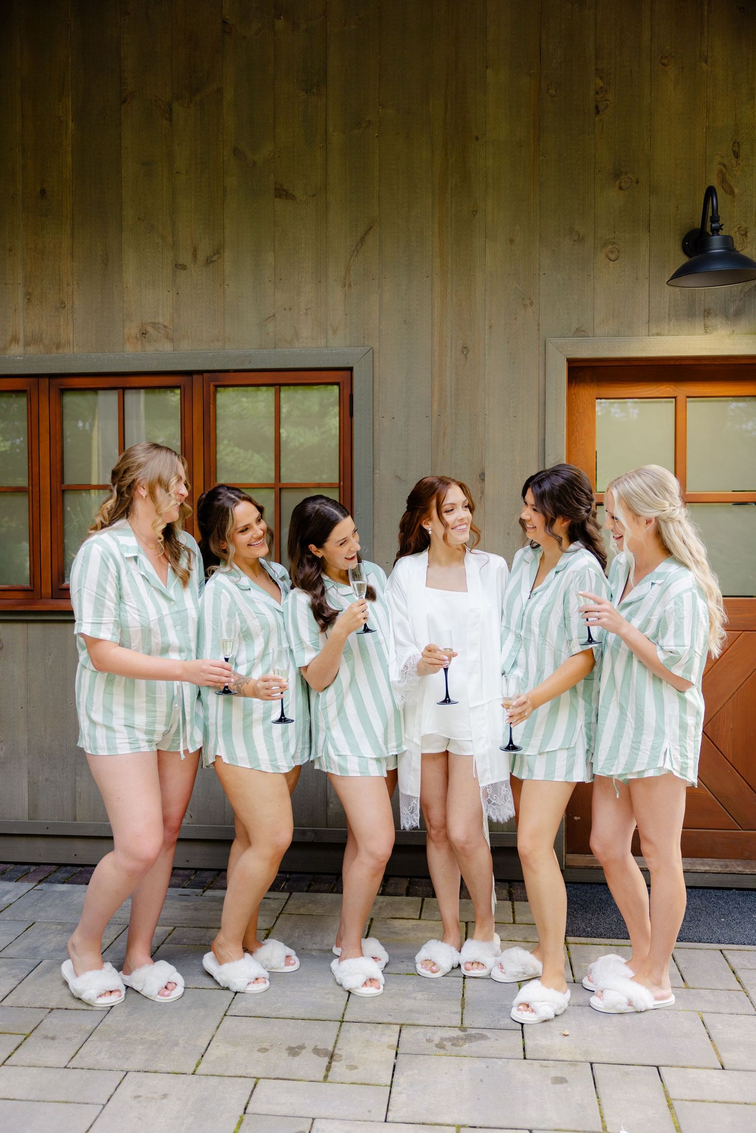 Bridesmaids in matching striped loungewear share candid laughs during pre-wedding preparations.