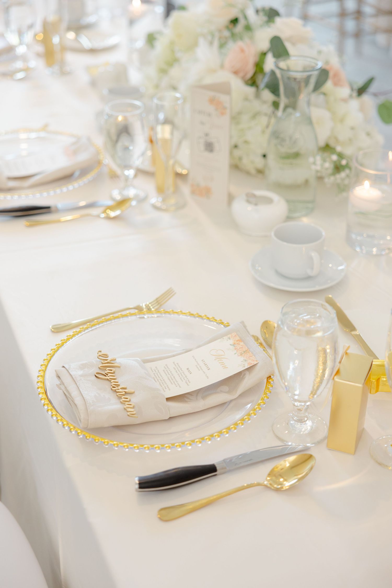 Elegant wedding table setting with gold accents and white floral centerpiece.
