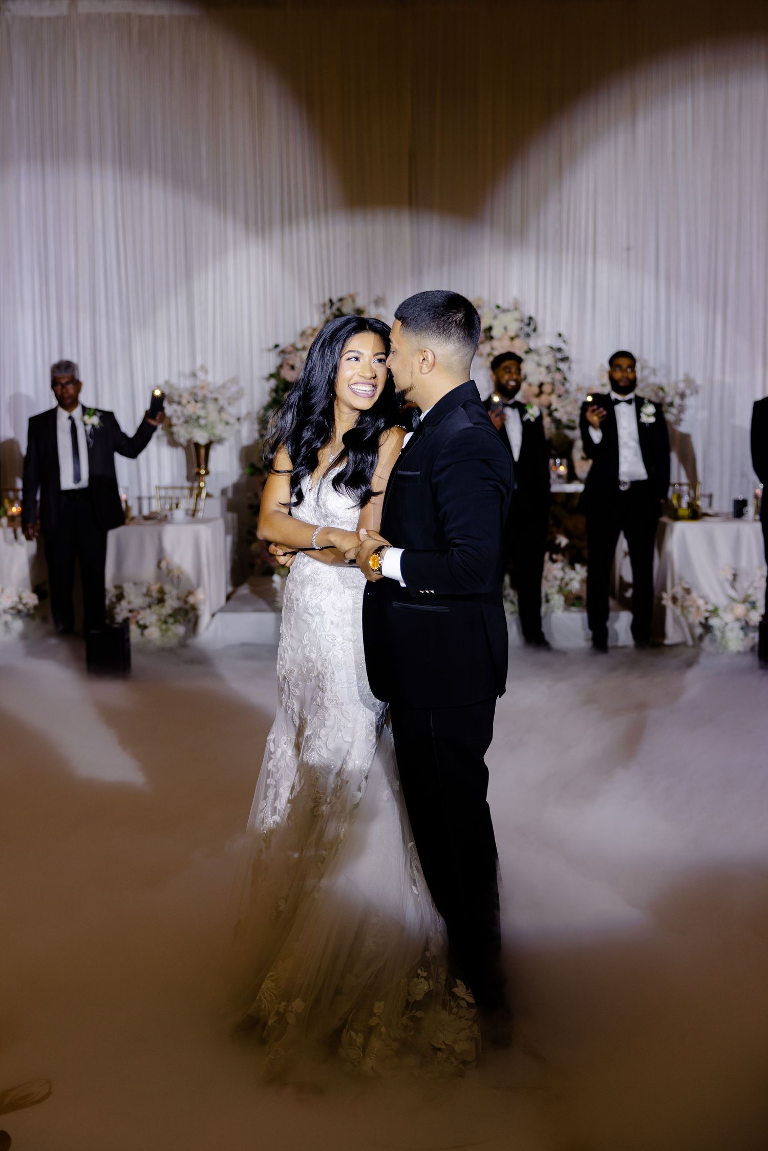 A couple toasts with champagne glasses in a black and white wedding photo.