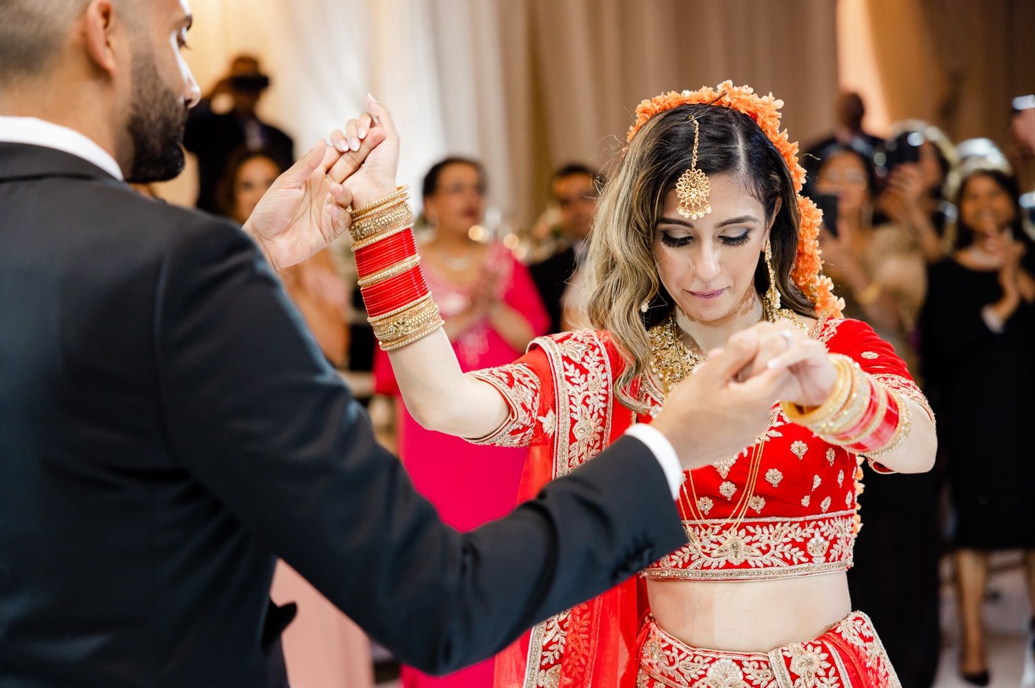 A couple performs a traditional dance at their wedding reception in elegant formal wear.
