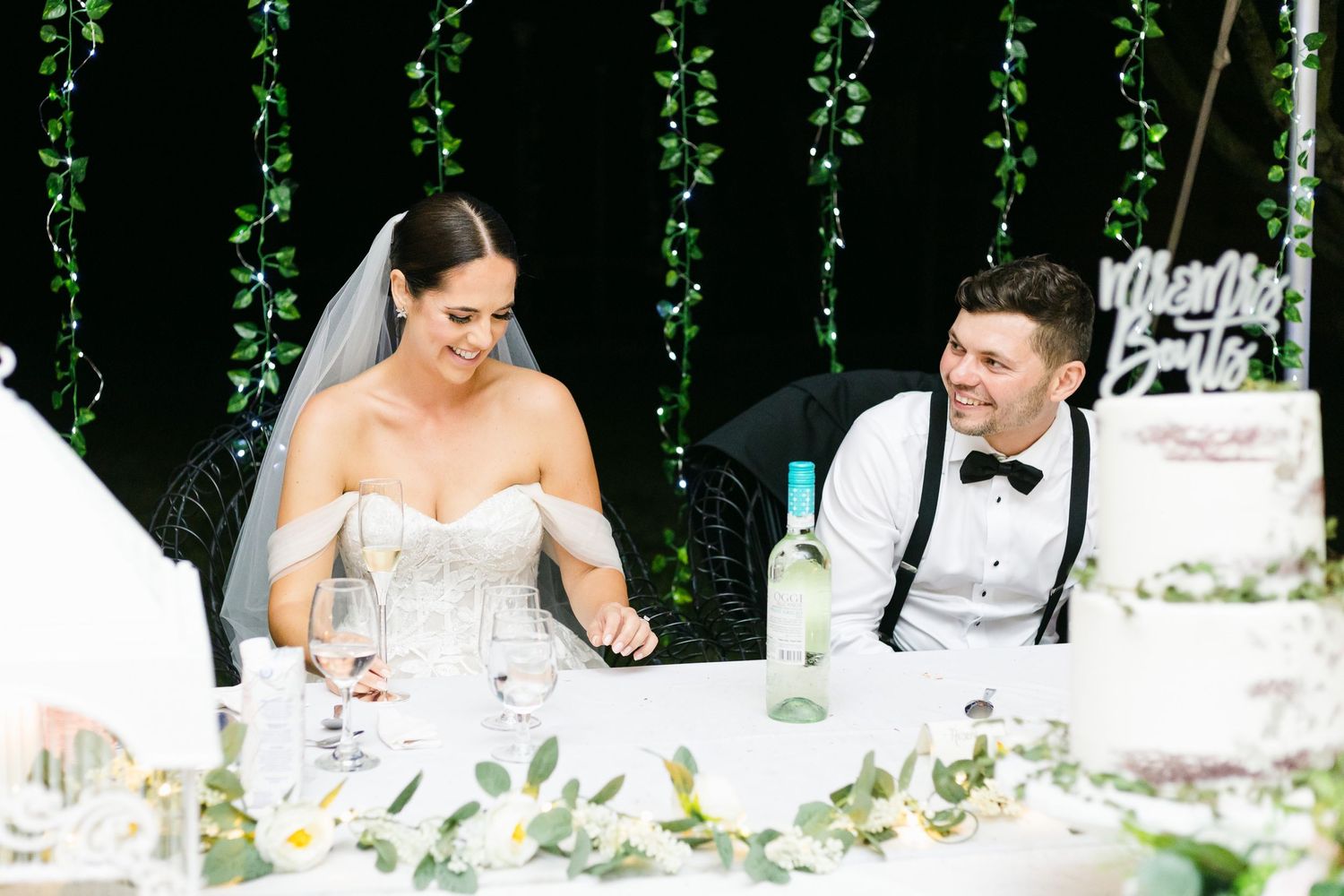 Reception table scene with elegant greenery backdrop and floral arrangements.