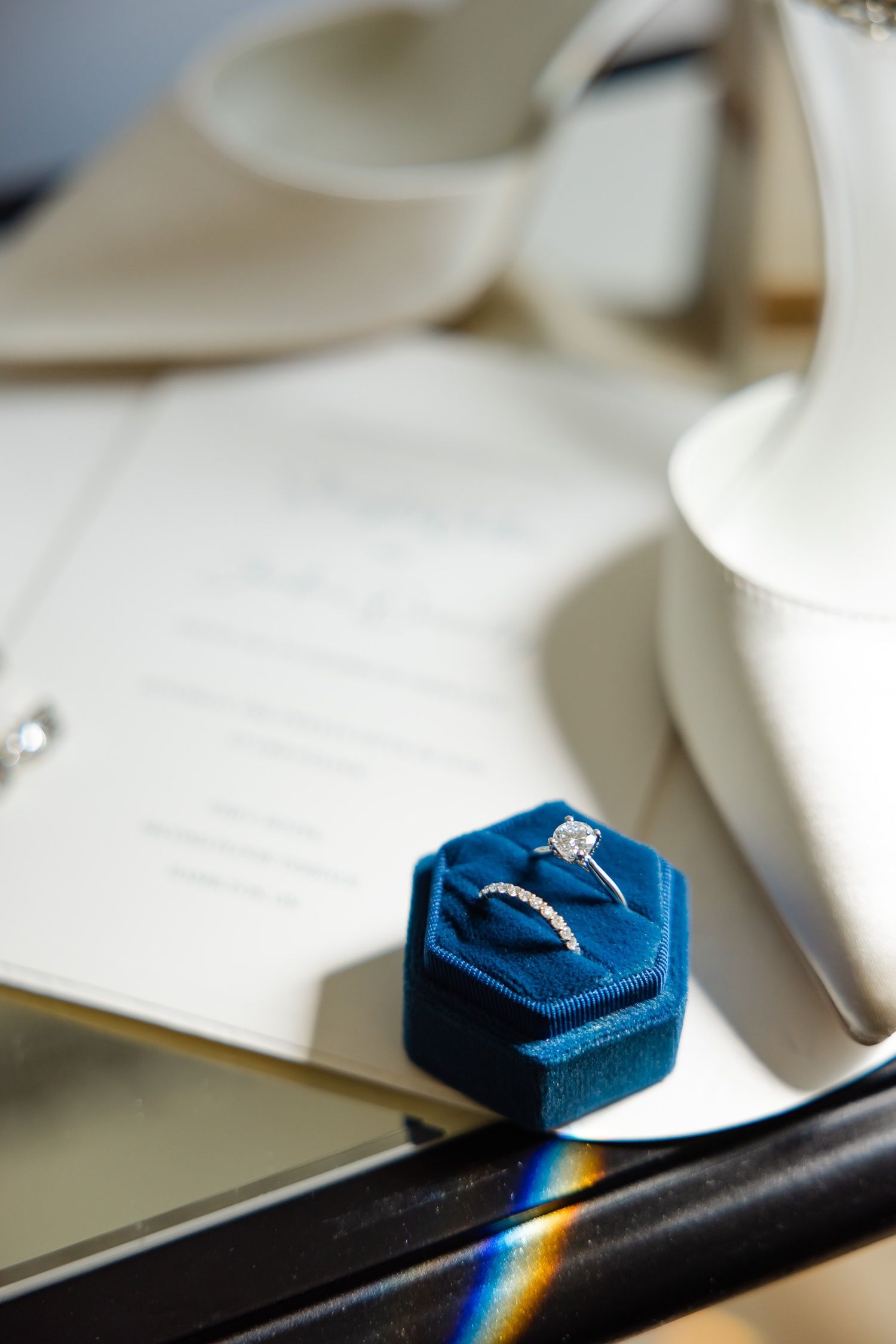 Wedding rings displayed in a blue velvet hexagonal box next to bridal accessories.