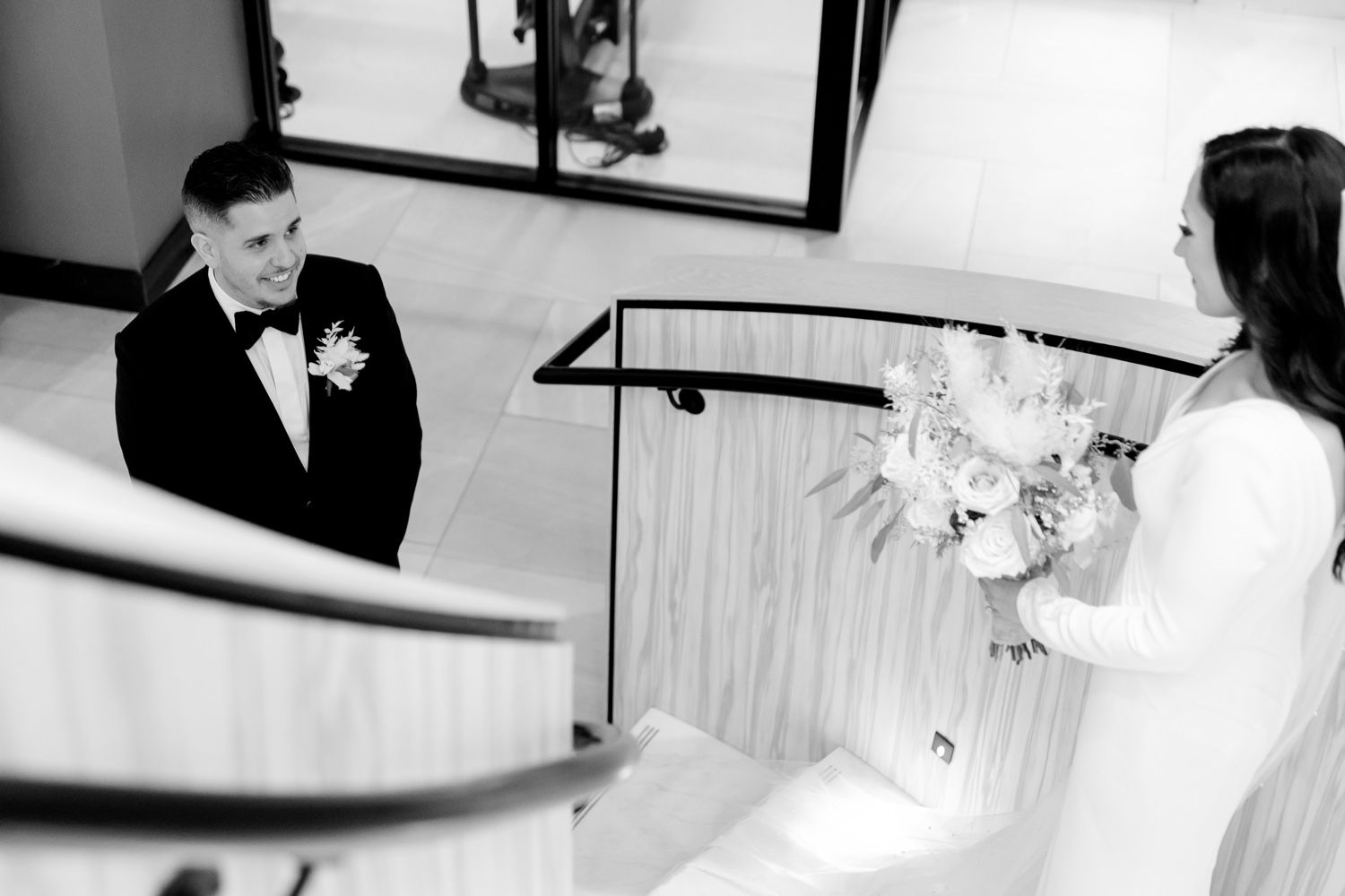 A black and white capture of a couple's first look moment on a grand staircase.
