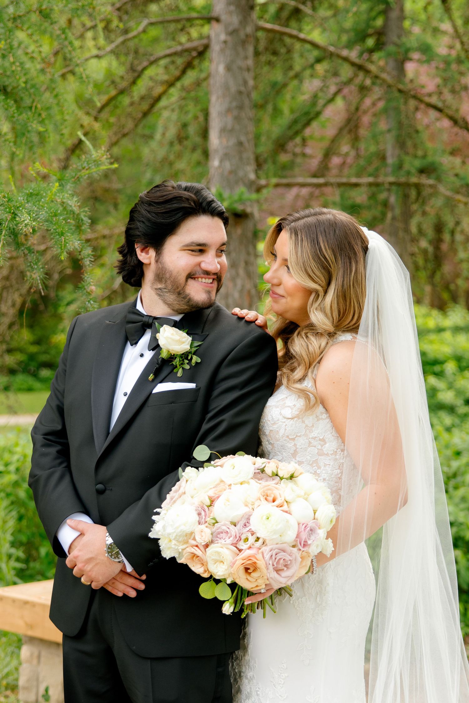Close-up of newlyweds sharing an intimate moment outdoors with lush greenery background.