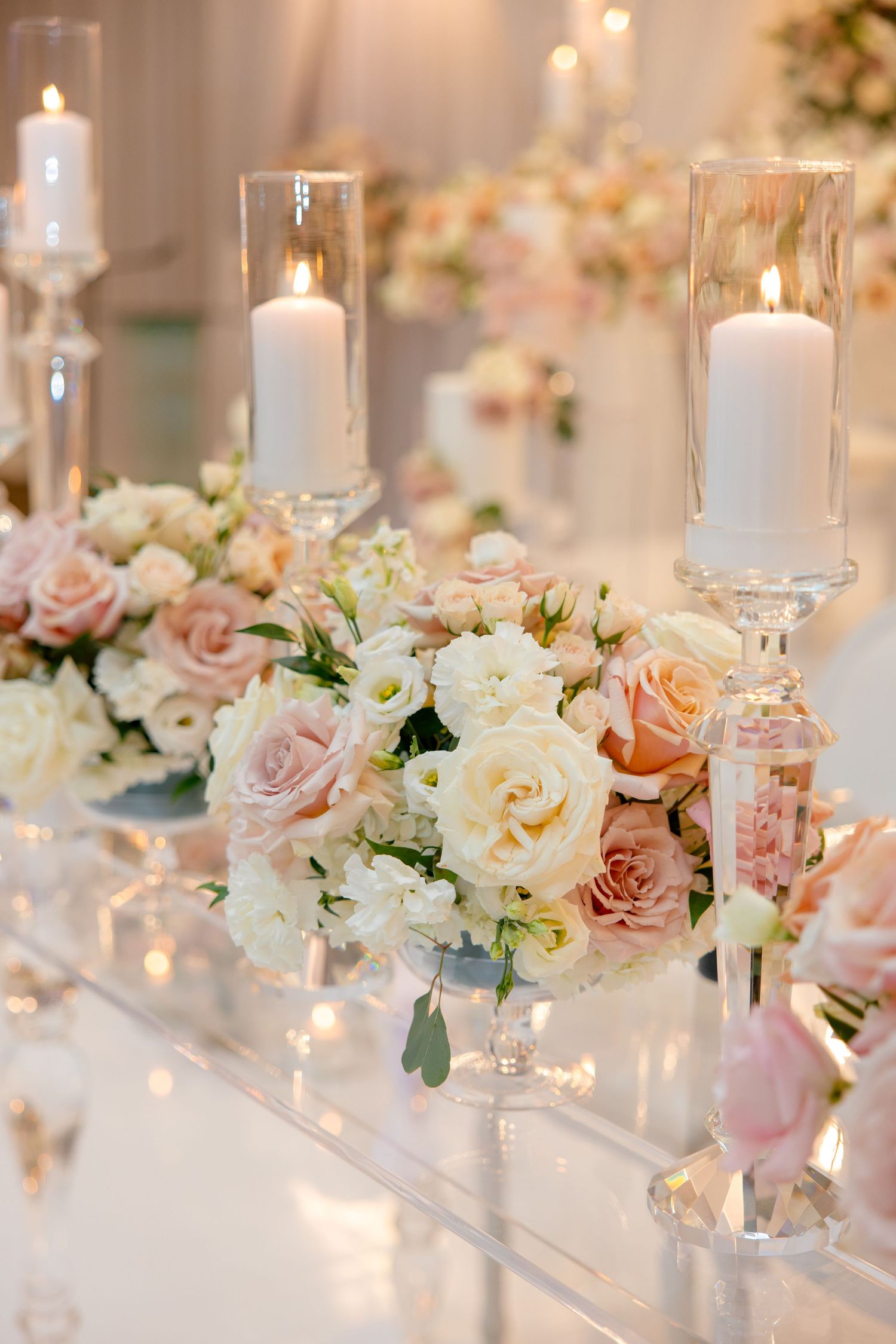 Crystal candle holders and blush rose arrangements creating romantic wedding table decor.