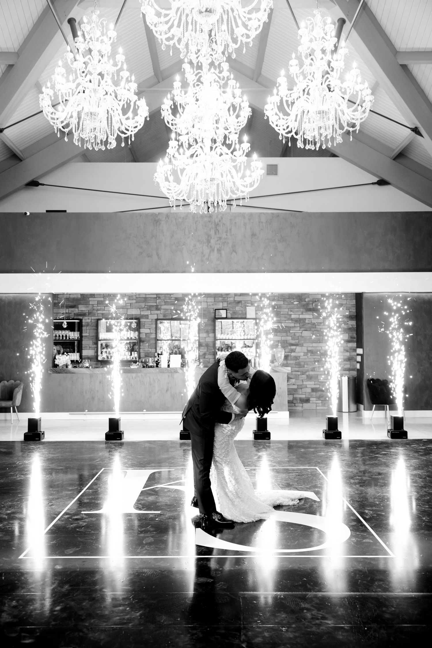 Dramatic dip during first dance under crystal chandeliers with illuminated monogram.