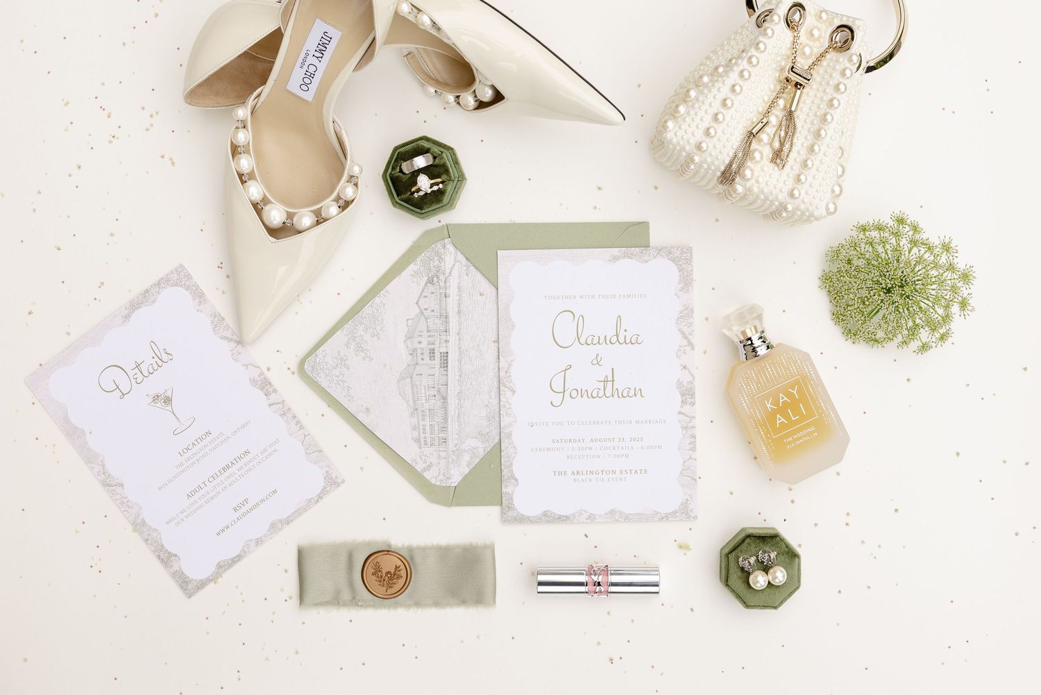 Flat lay of wedding stationery featuring elegant invitations, envelopes and decorative elements in soft white and sage colors.