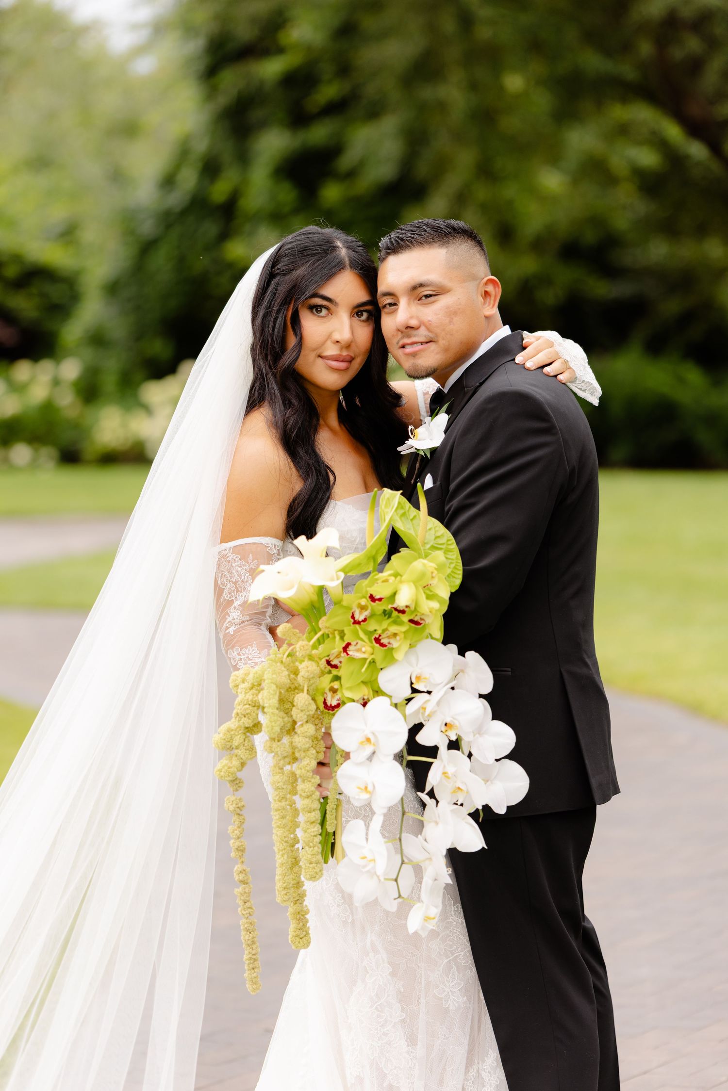 A romantic wedding photoshoot series showing a couple embracing outdoors with a stunning white and yellow orchid bouquet.