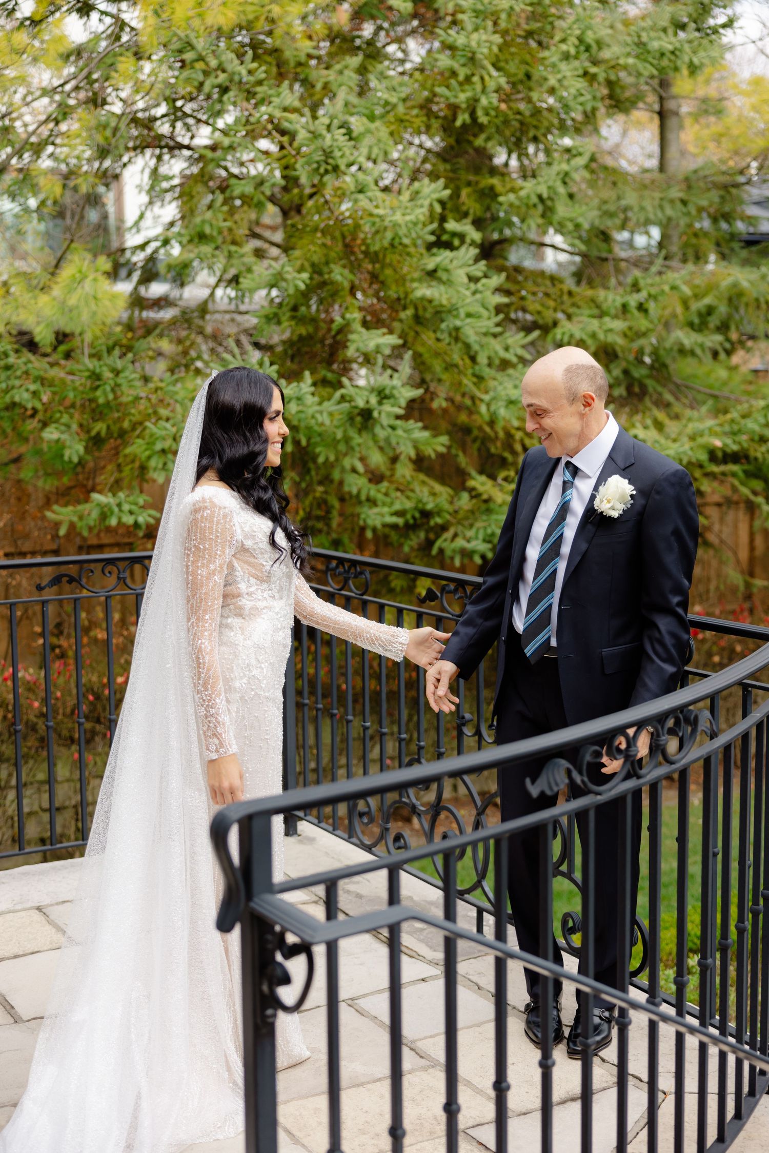 Intimate wedding moment shared on stone steps with decorative iron railings and autumn trees.