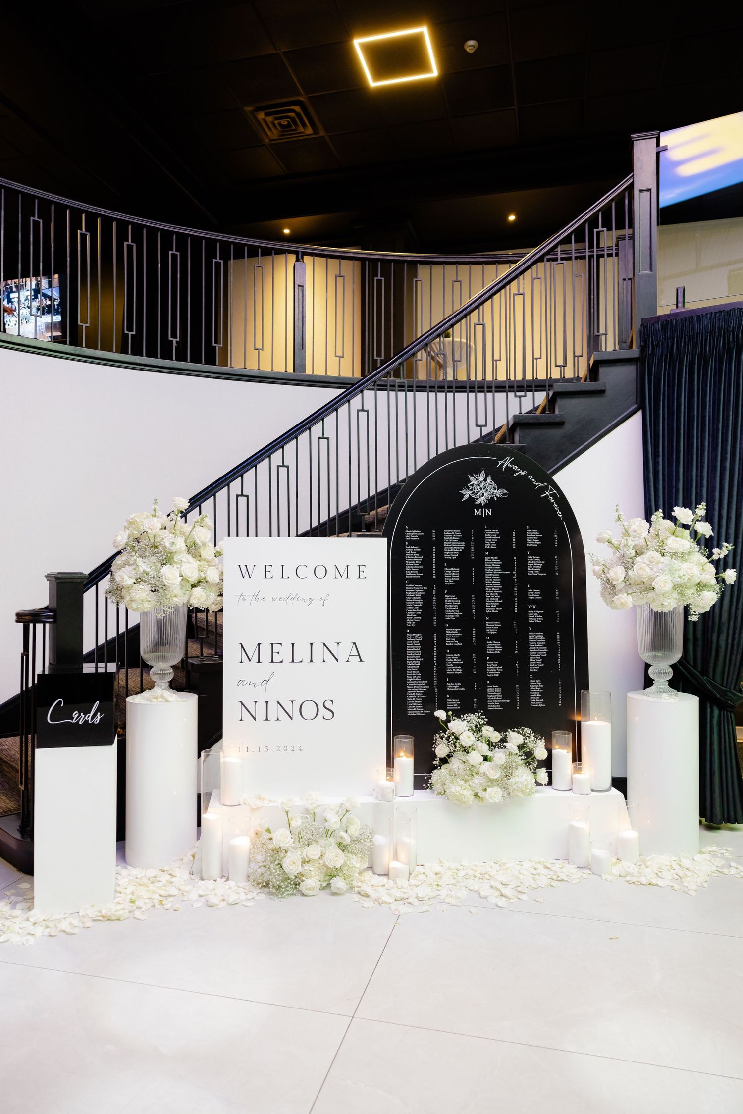 Wedding welcome display with white flowers and candles at venue entrance.