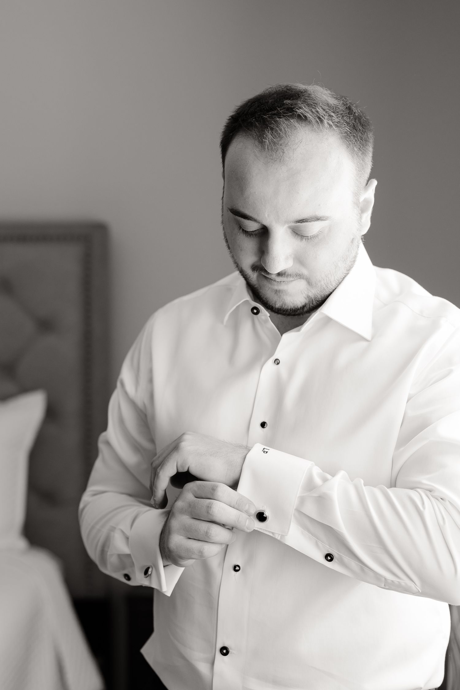 Someone adjusts the sleeve of a crisp white dress shirt while getting ready.