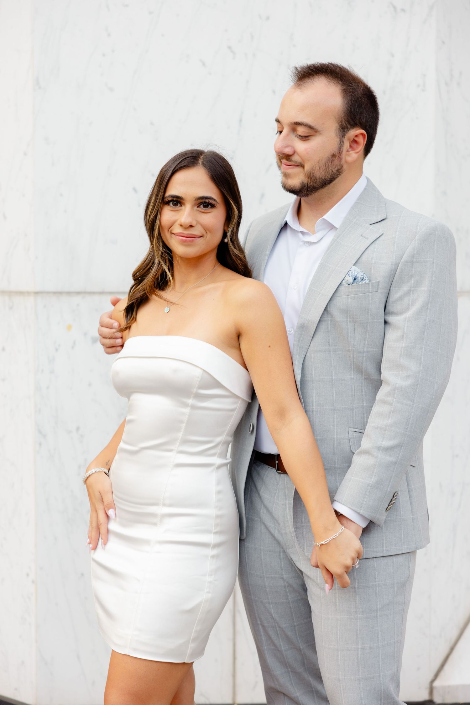 Intimate portrait of couple in coordinating white and grey formal attire.