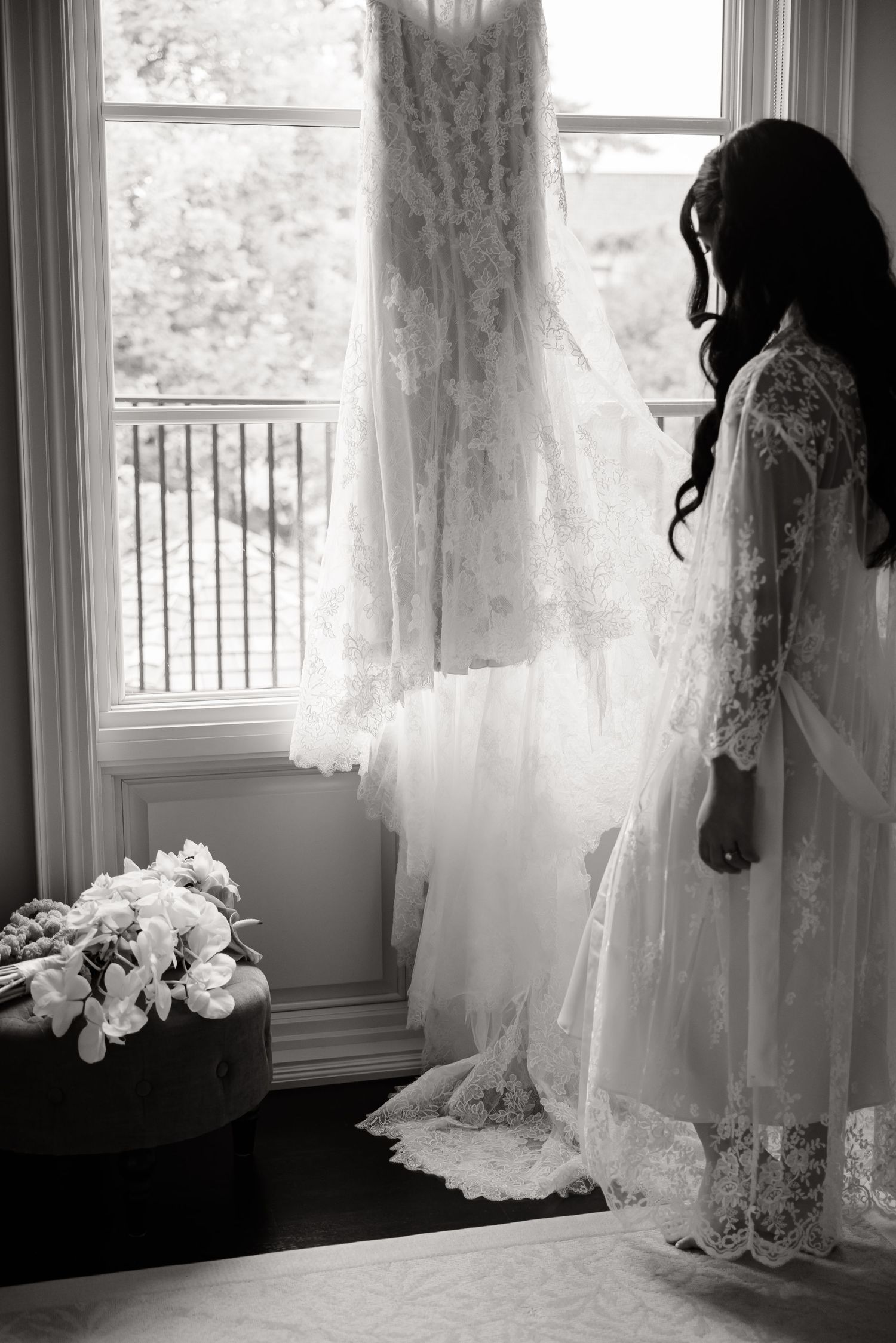 A series of ethereal white wedding dresses hang in sunlit windows creating a romantic bridal boutique display.
