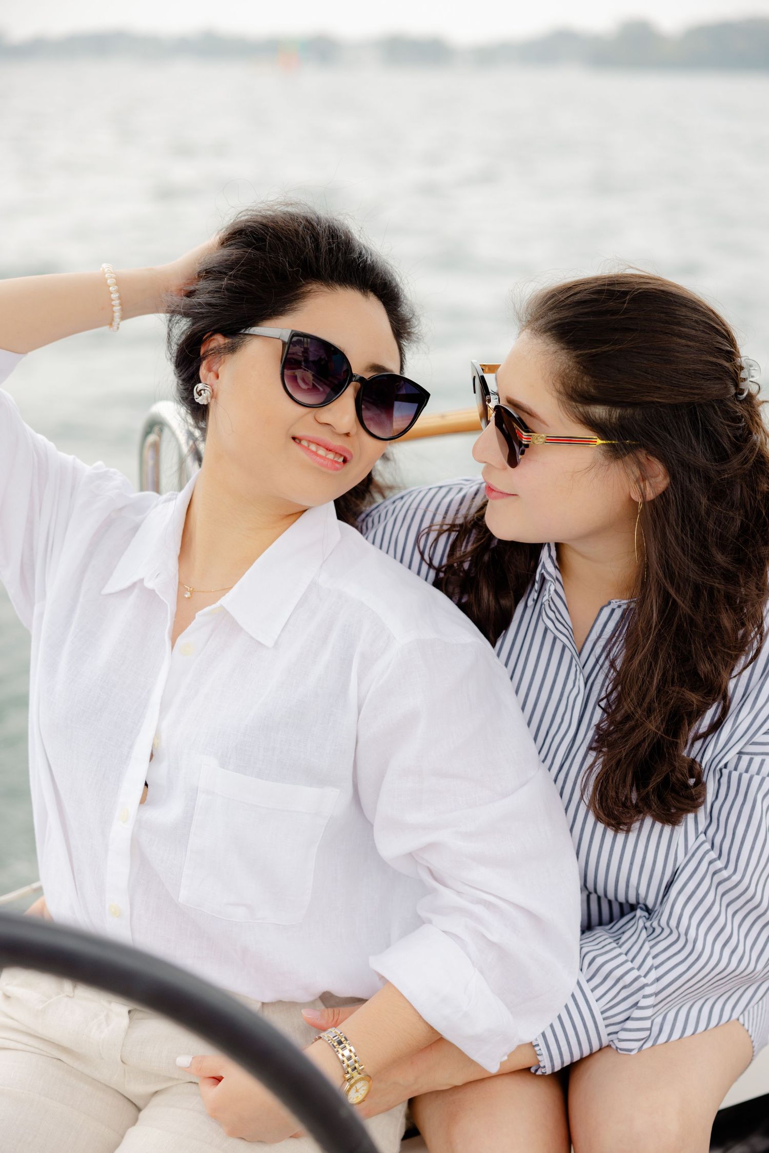 Two companions enjoying a sunny boat ride wearing sunglasses and casual summer attire.