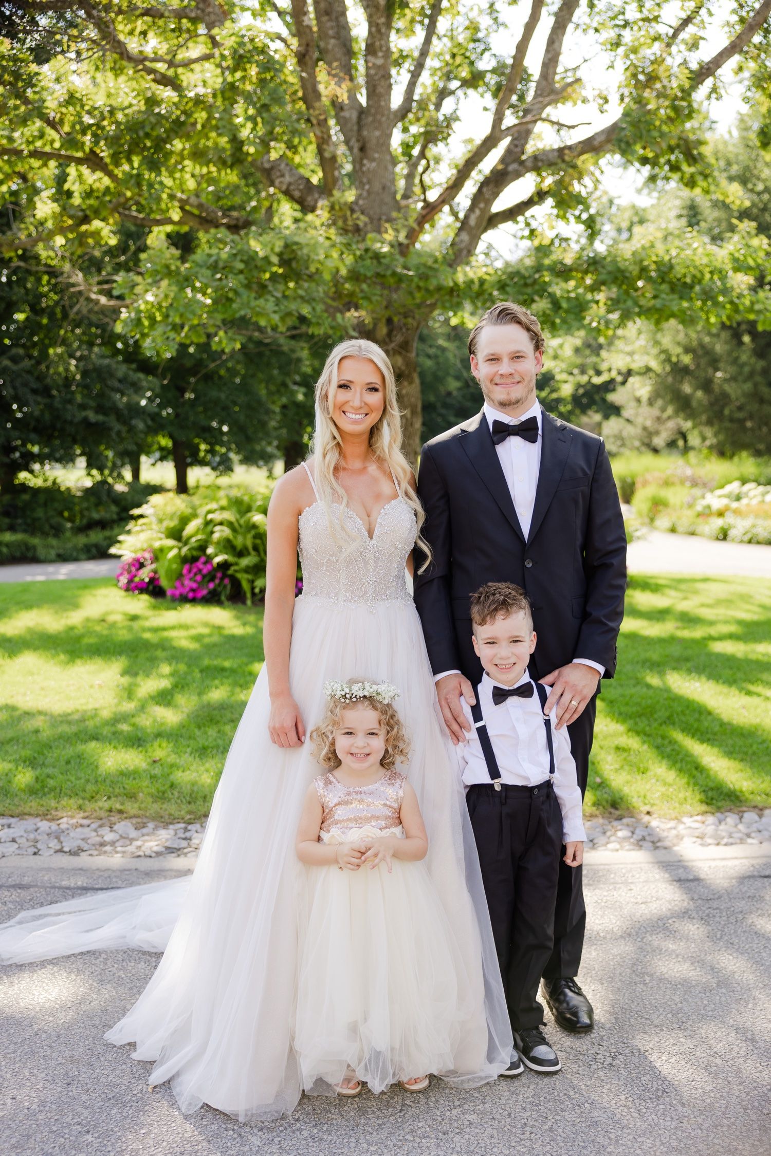 Wedding portrait of a family in formal attire standing together in a lush garden setting.