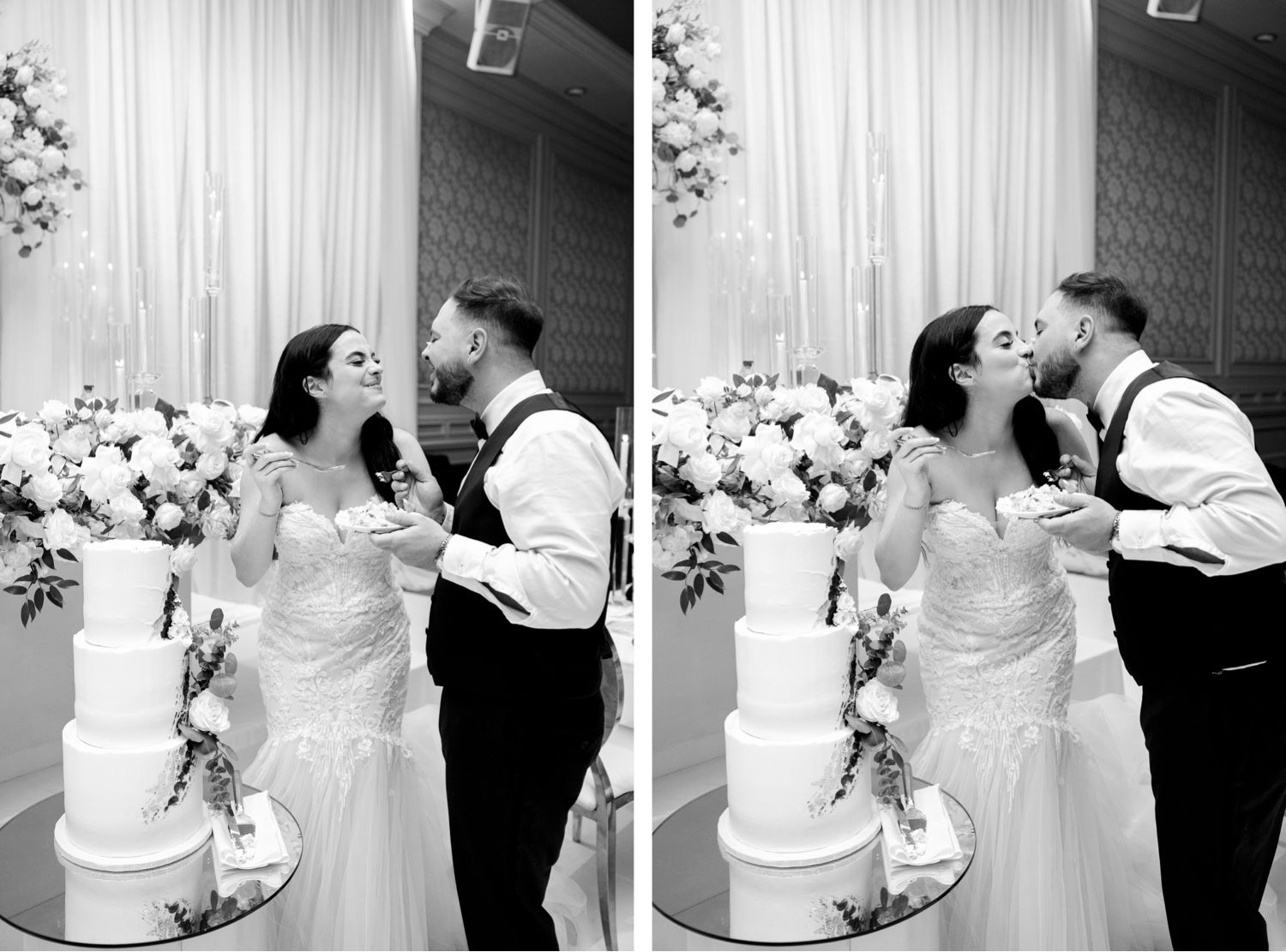 Black and white capture of couple laughing while sharing wedding cake at reception.