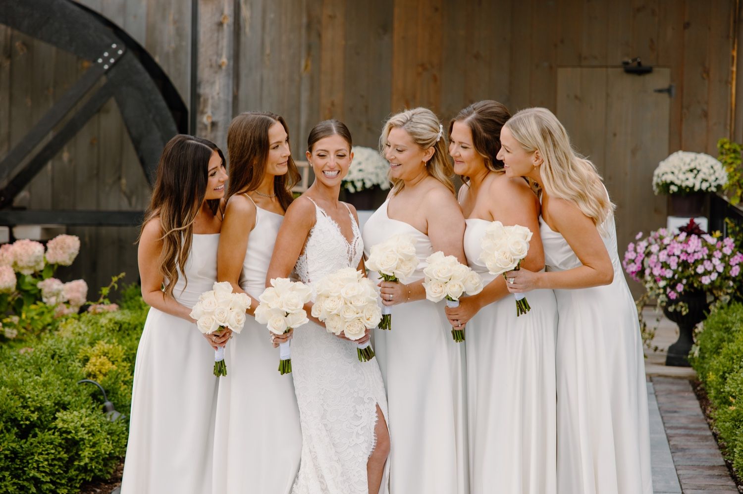 Bridal party in white dresses sharing a joyful moment together outdoors.