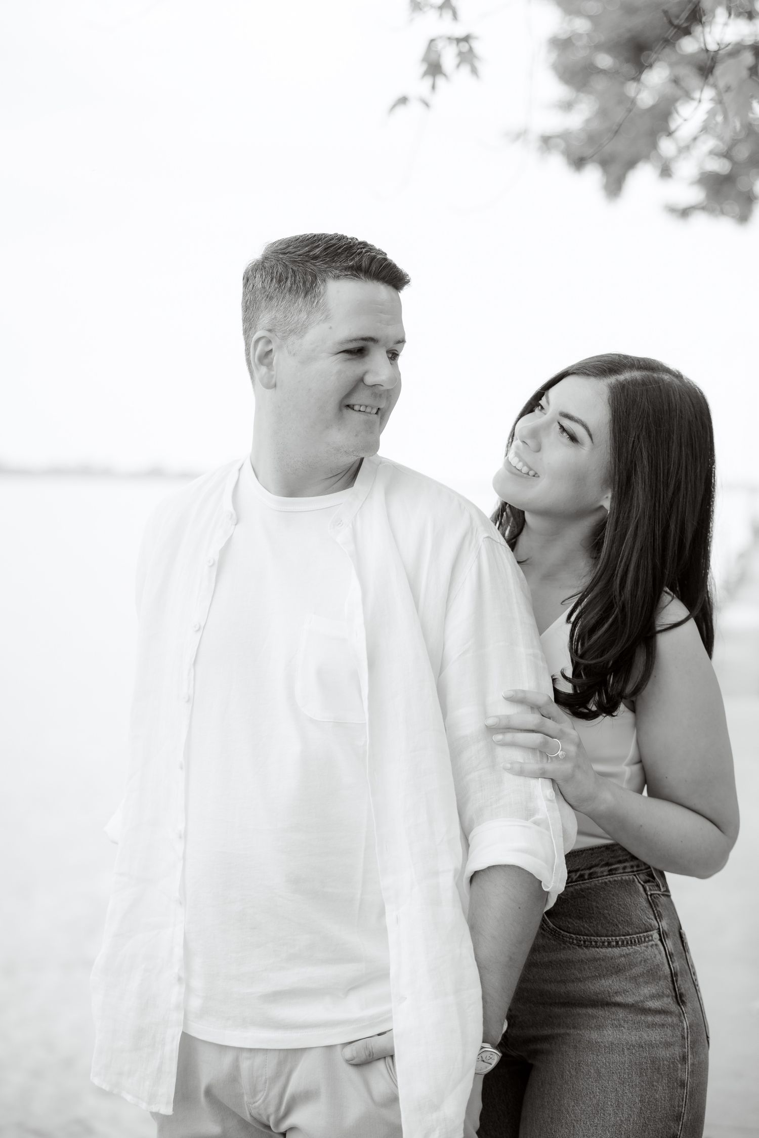 A romantic black and white portrait of a couple sharing an intimate moment by the water.