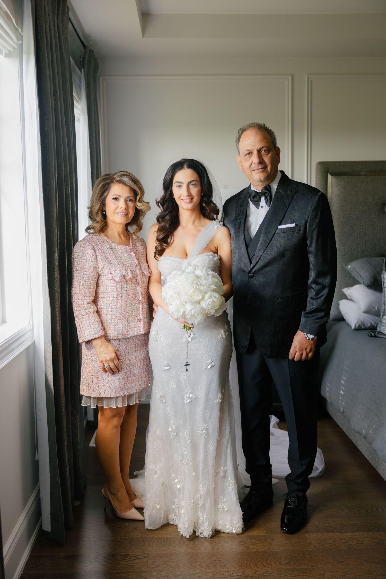 A formal wedding portrait in a bright room with hardwood floors and elegant decor.