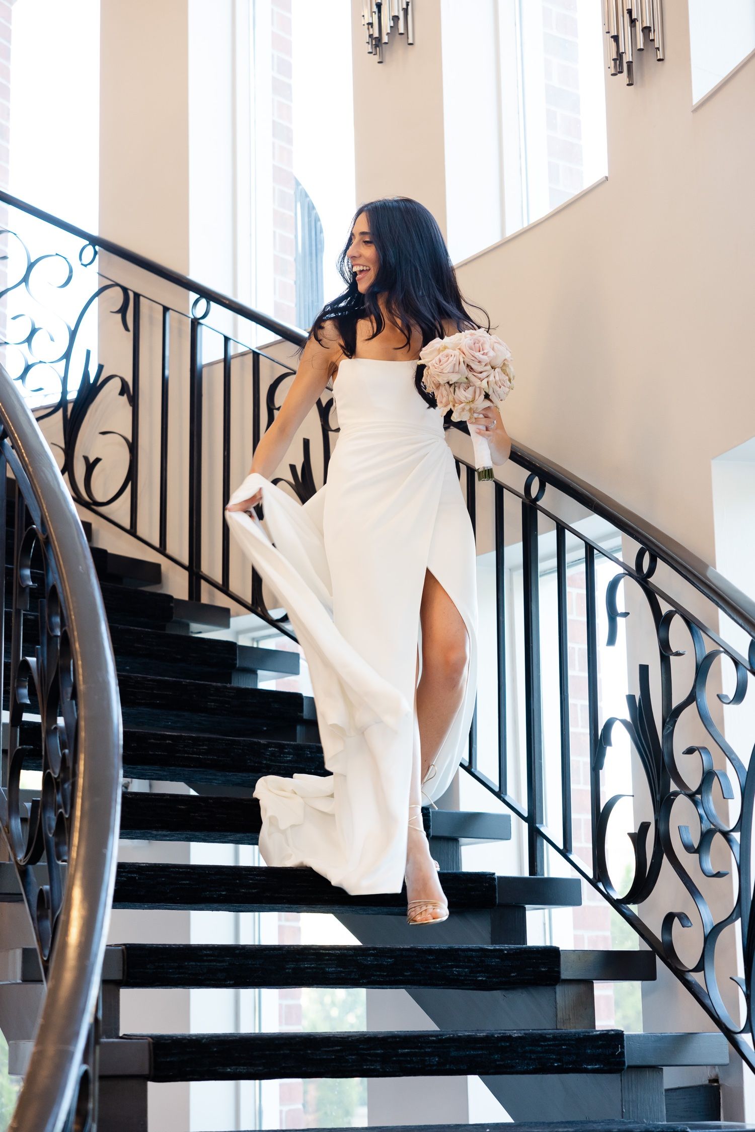 White gown with high slit photographed on elegant black staircase with iron railings.