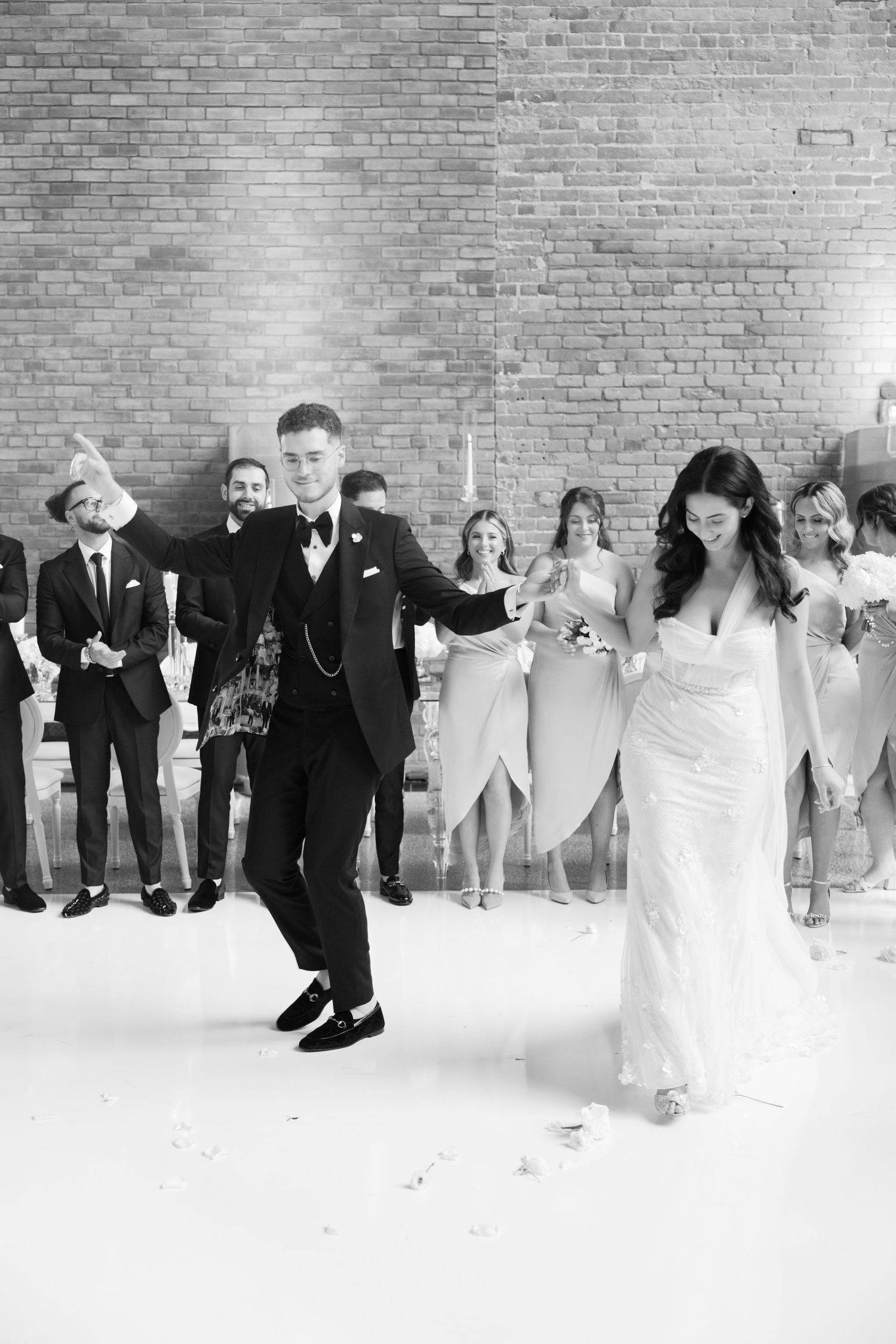 Wedding party celebration in a modern industrial venue with white flooring and brick walls.