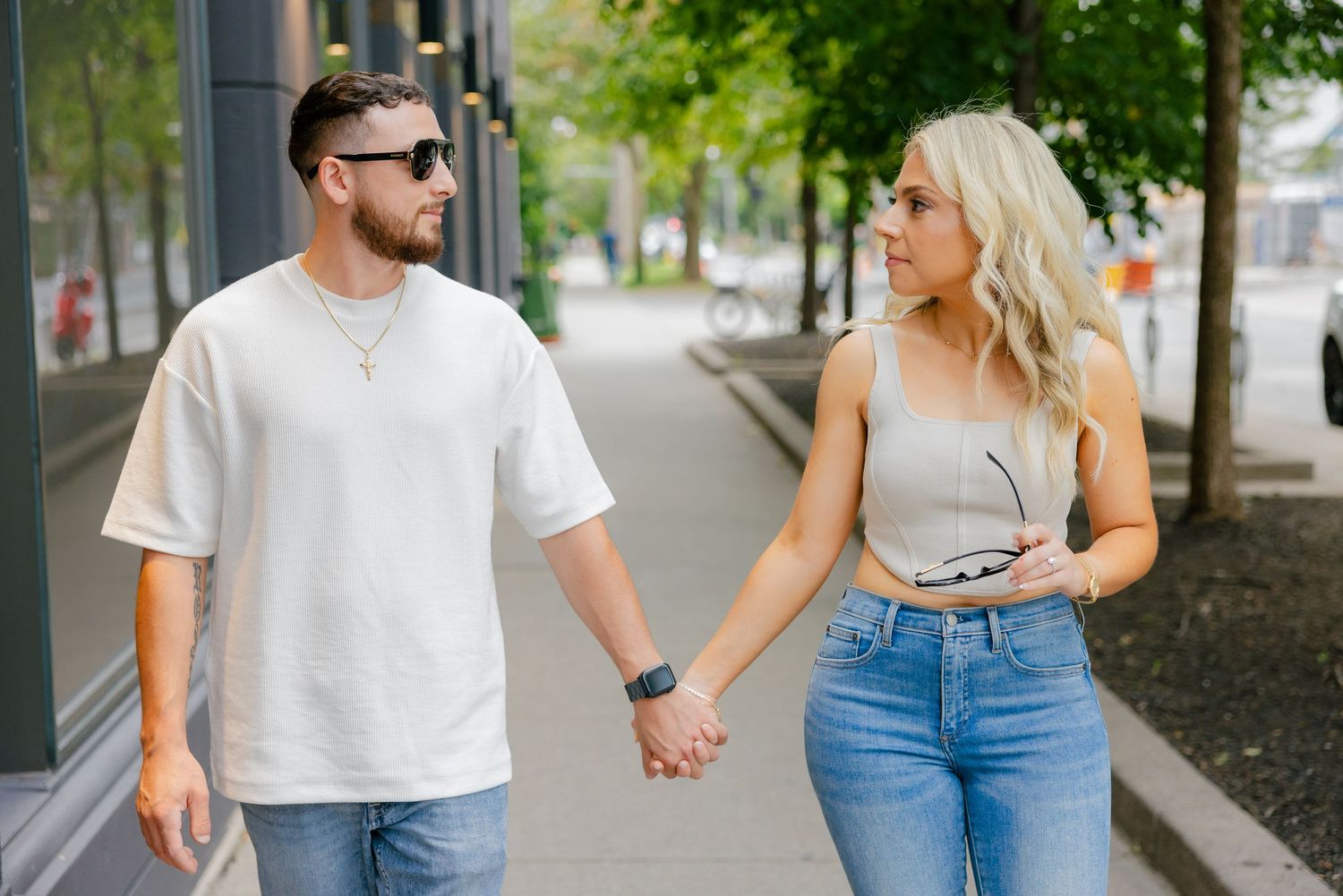 Stylish couple in denim and white clothing strolling together on an urban street.