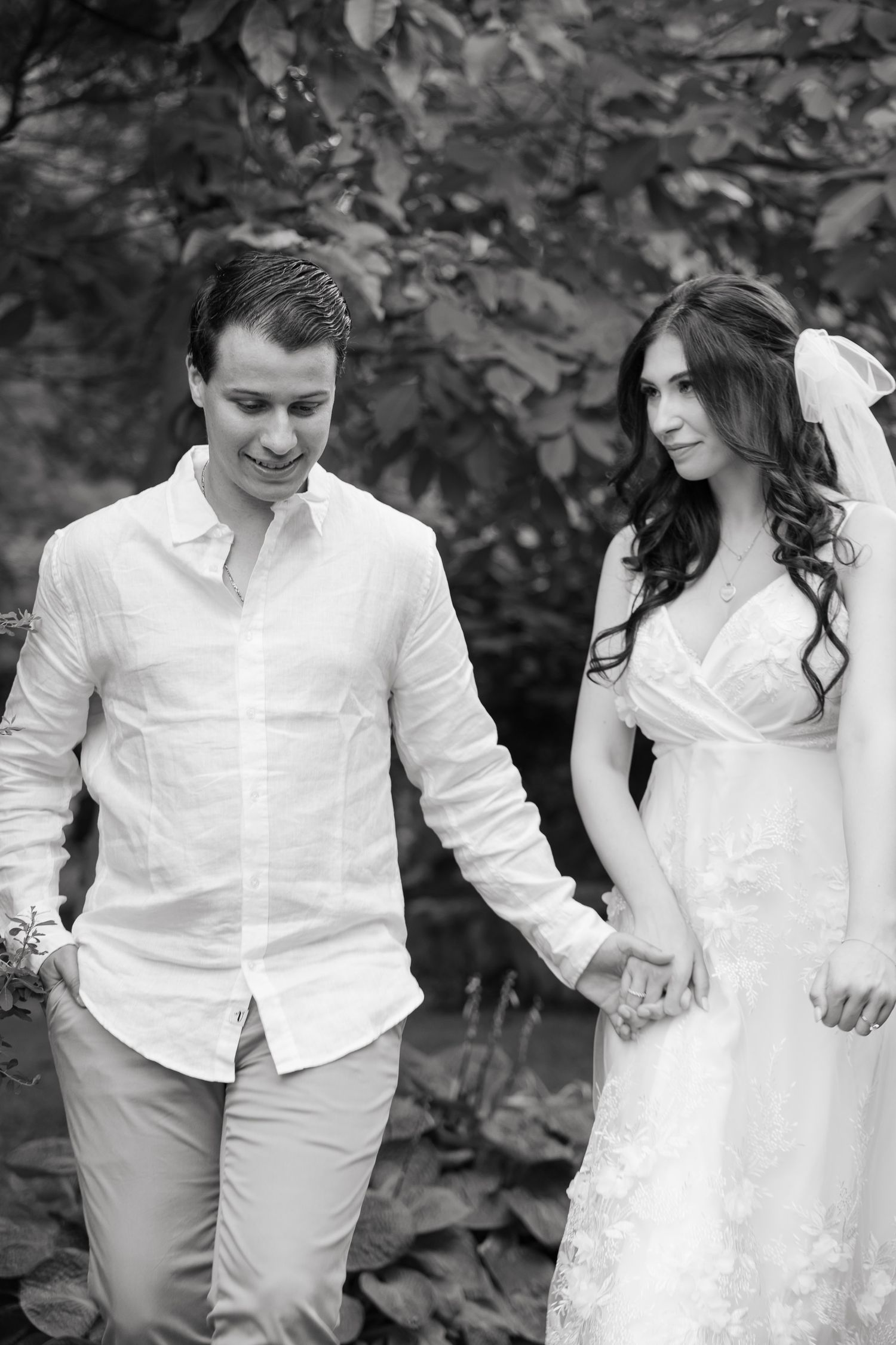 Black and white photo of a couple holding hands in an outdoor garden setting.