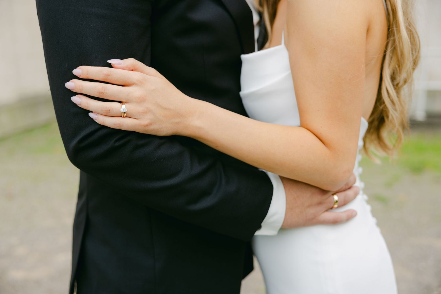 Close up of couple embracing, showing bride in white dress and groom in black suit holding each other.