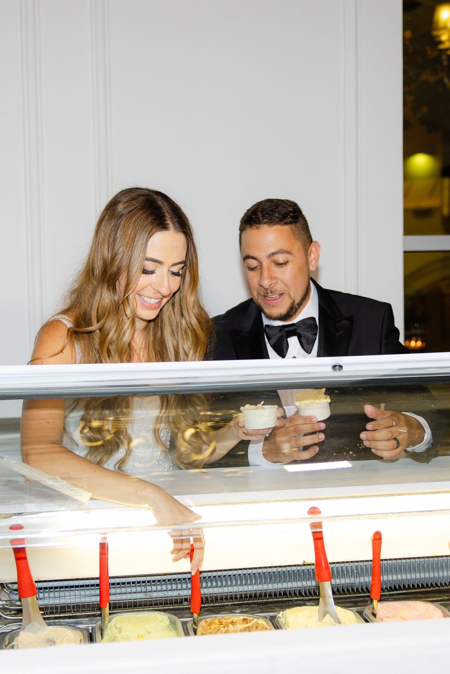 Couple sharing a moment while selecting flavors from a gelato cart at a formal event.