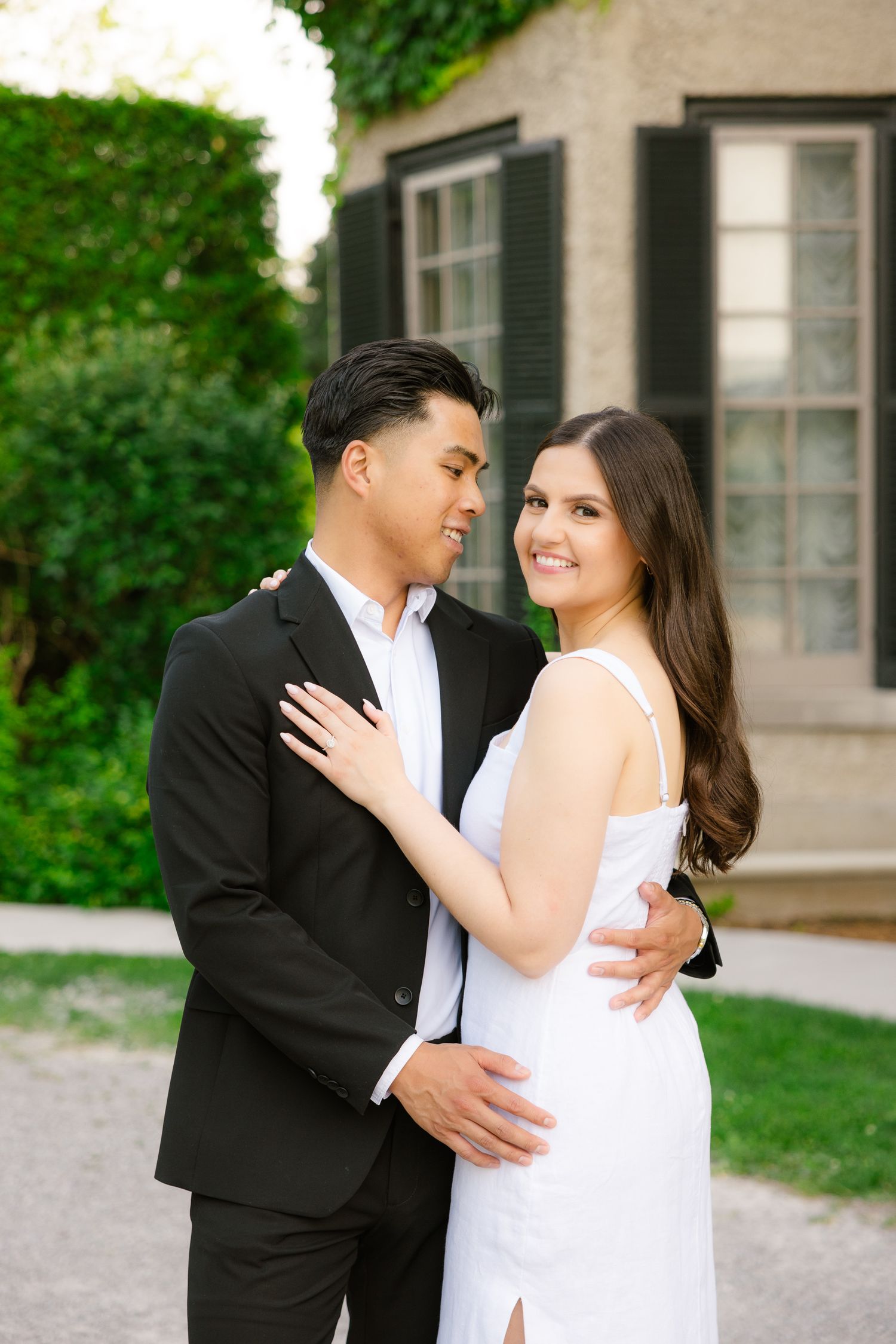 Romantic portrait of couple in formal wear against historic building facade.