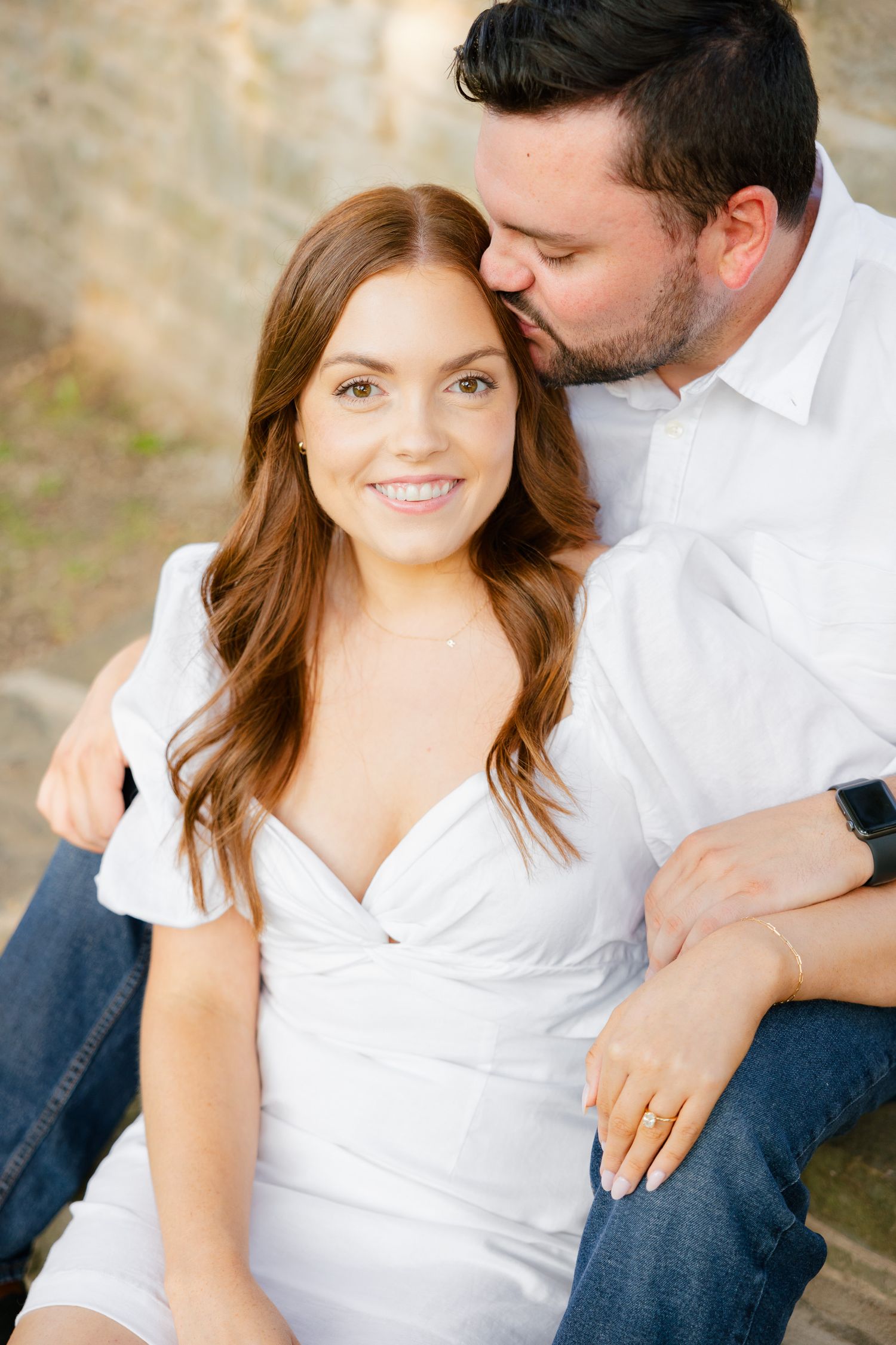 Close-up portrait of couple in white sharing a tender moment outdoors.