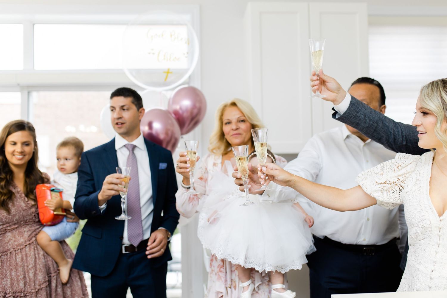 Celebration gathering with champagne toasts and pink balloons.