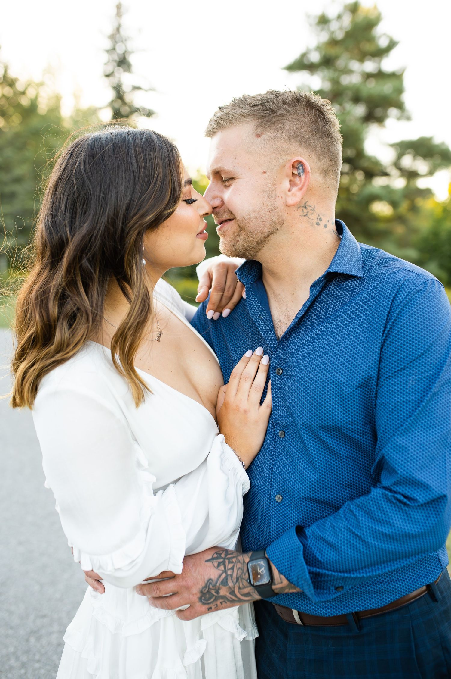 Intimate moment captured between couple in white dress and blue shirt during outdoor photo session.