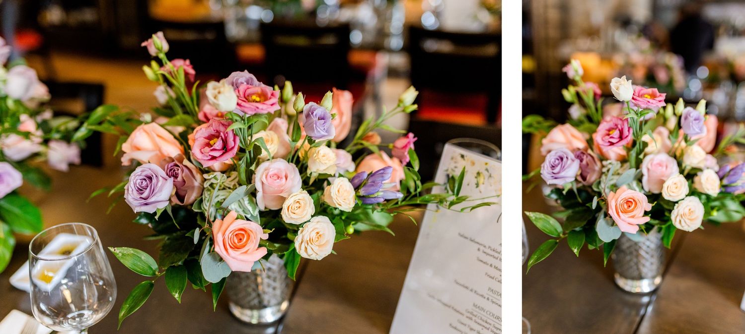 Beautiful pink and peach rose arrangements in silver vases on wooden dining table.