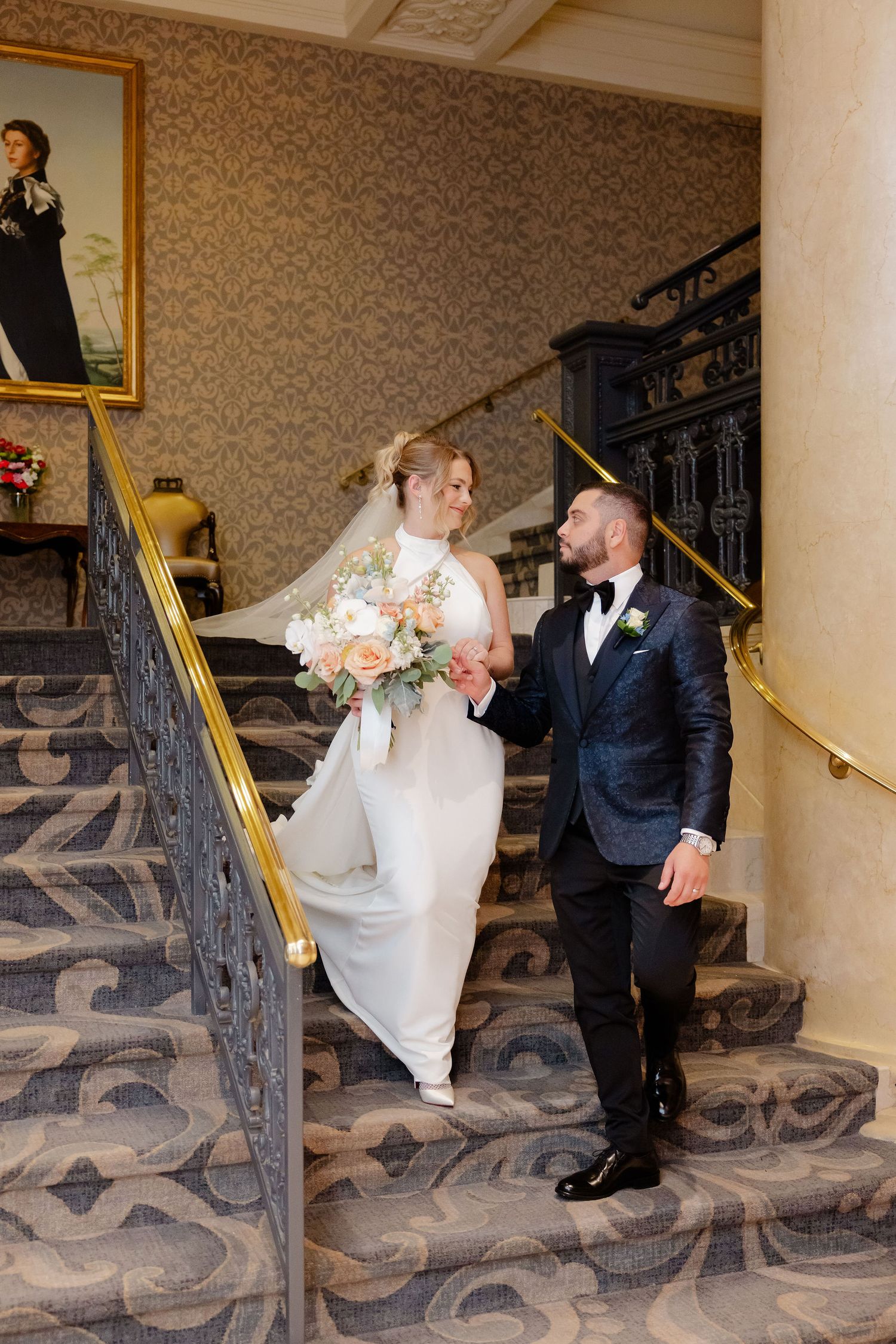 A romantic wedding moment captured on an elegant staircase with ornate details and golden railings.