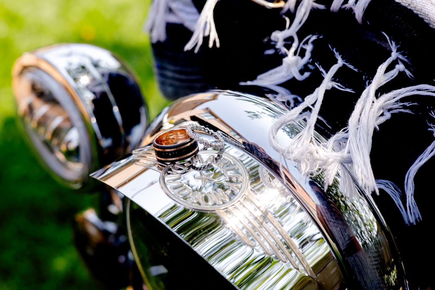 Detail shot of chrome motorcycle trim and headlight with wedding rings.